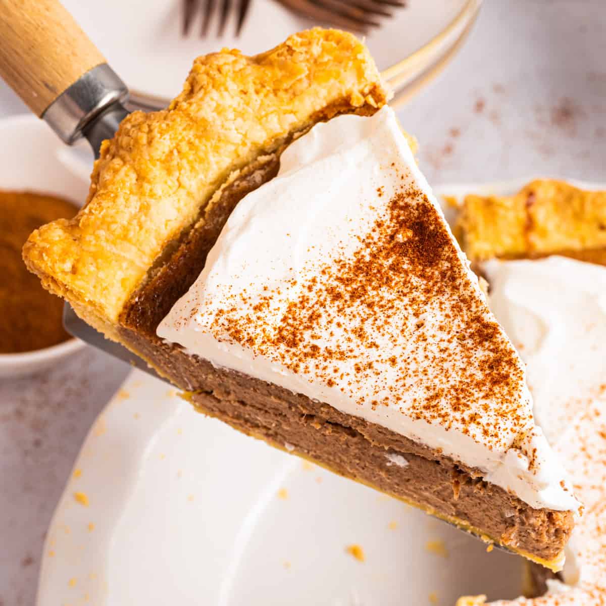 Cinnamon Pie A slice of Cinnamon Pie topped with whipped cream - on a spatula.