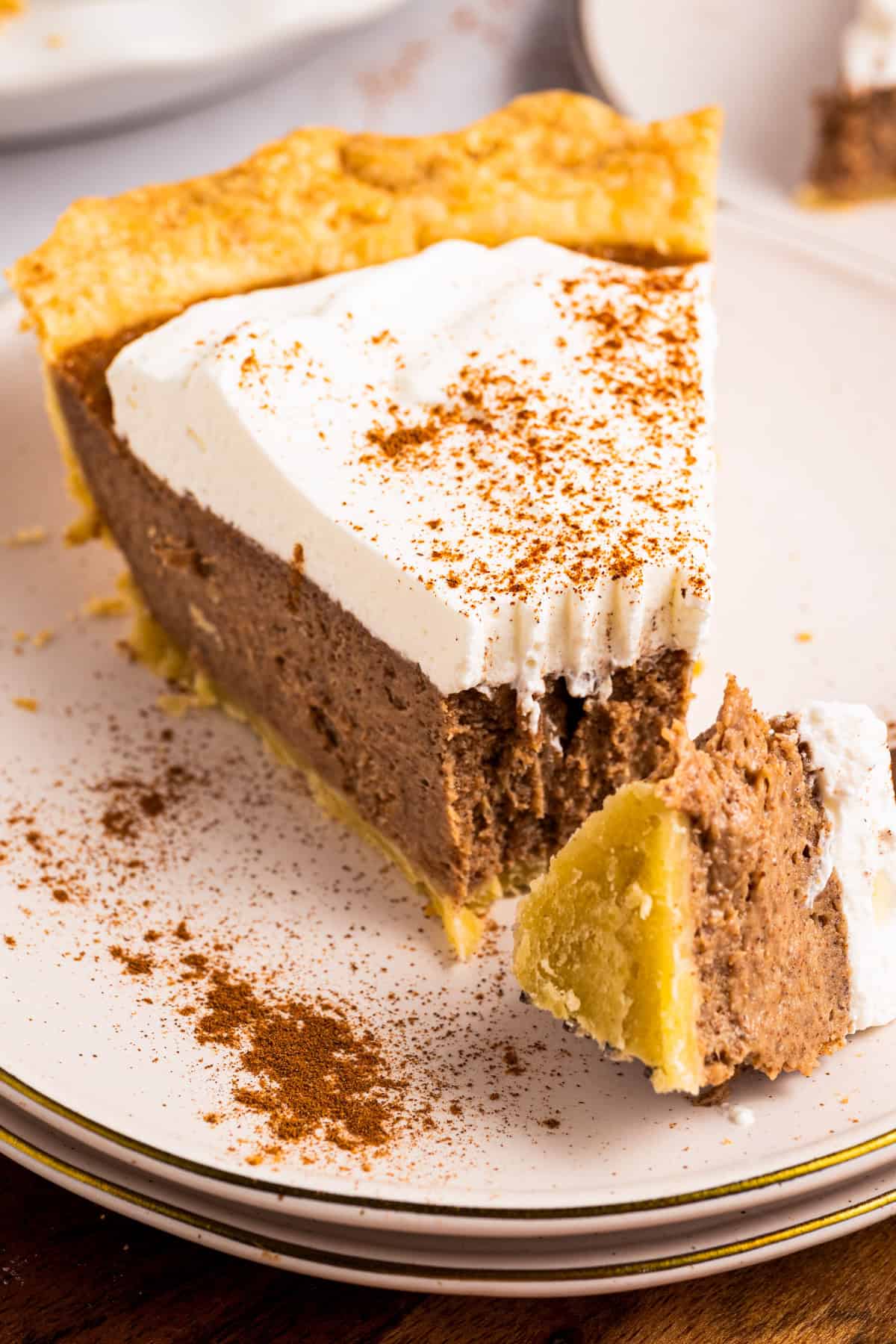 Cinnamon Pie A slice of Cinnamon Pie topped with whipped cream on a plate (with a bite sliced by a fork).