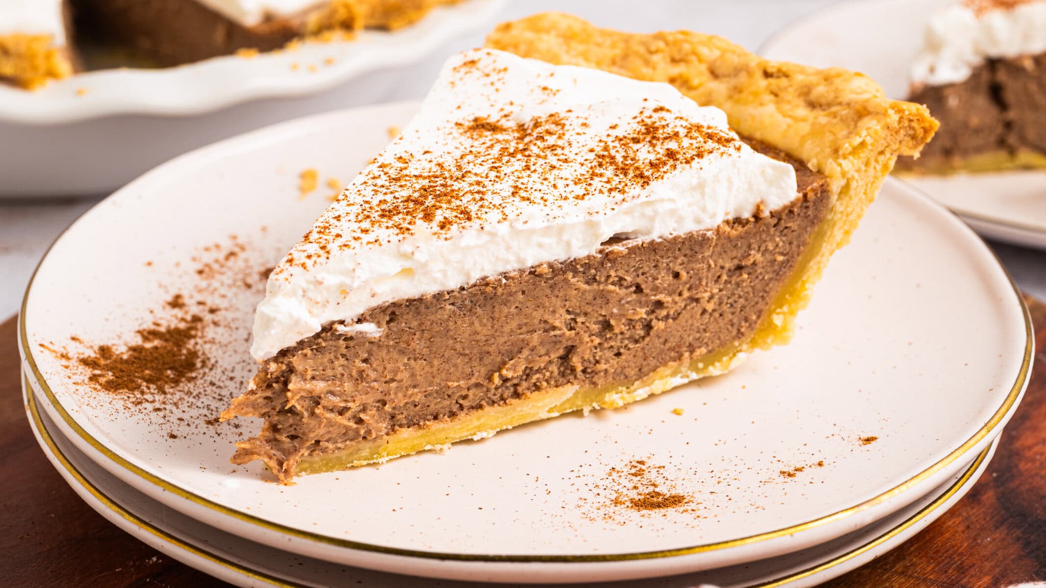 Cinnamon Pie A slice of Cinnamon Pie topped with whipped cream - on a white plate.