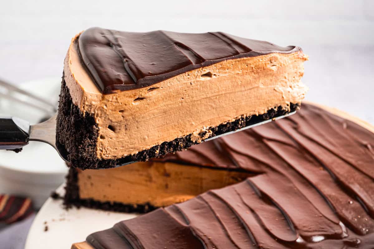 A slice of Mocha Cheesecake on a pie spatula lifted above the cake.