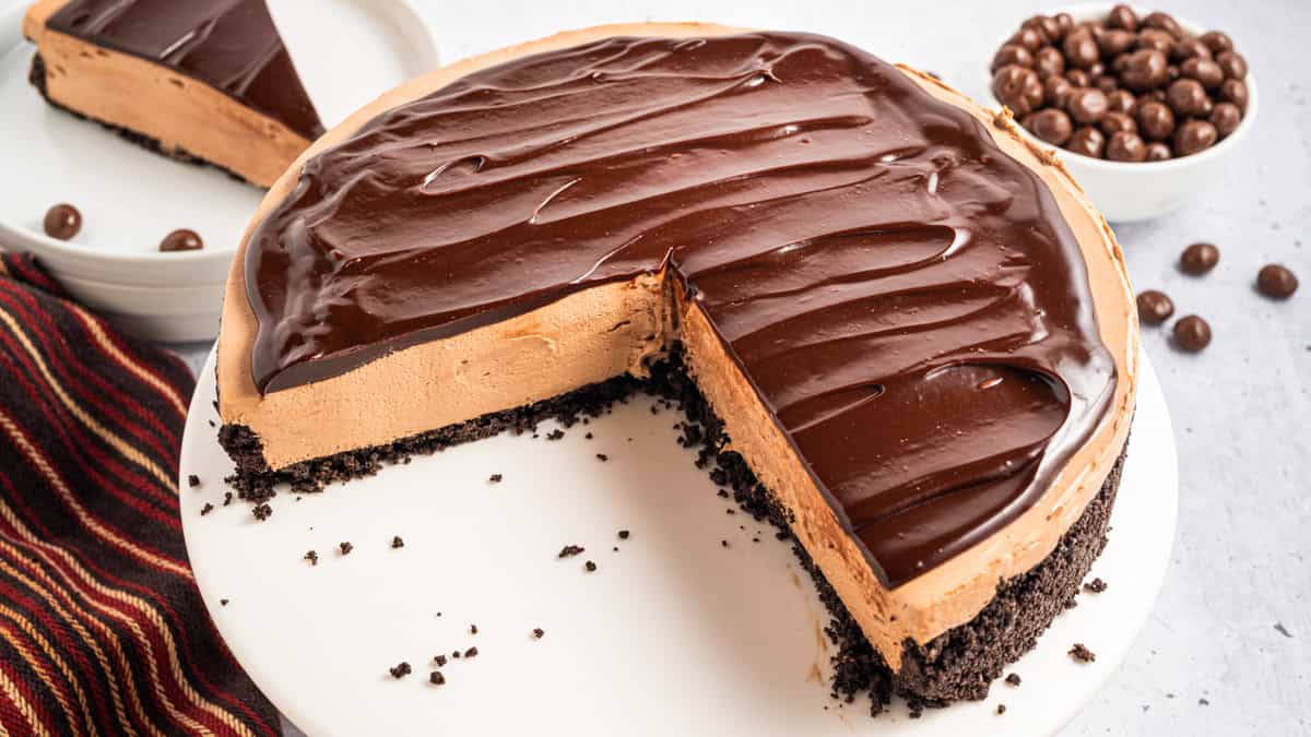 Mocha Cheesecake with a large part of it cut out, revealing the filling inside the cake - on a white platter.