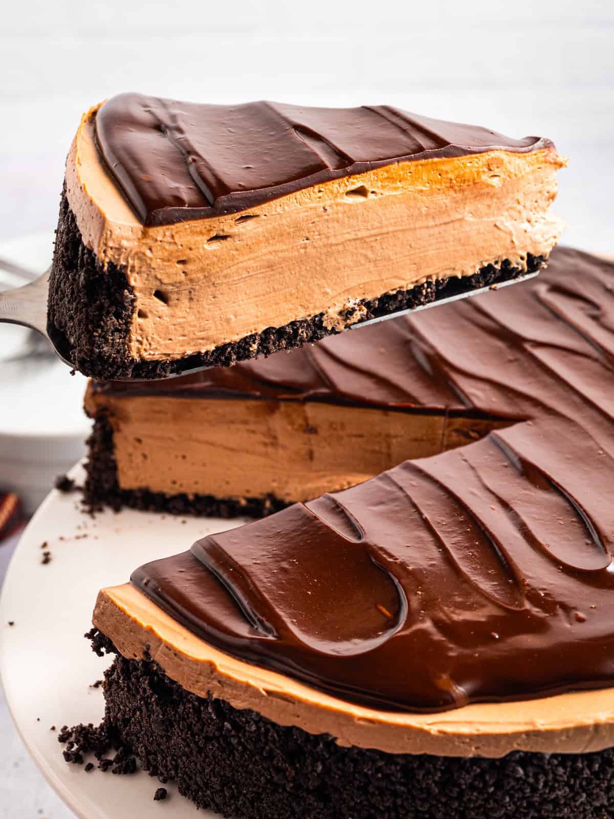 A slice of Mocha Cheesecake on a pie spatula being lifted above the cake.