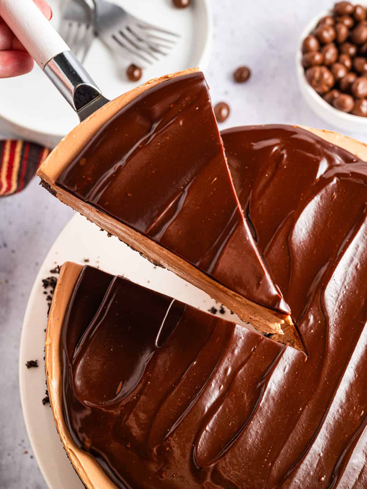 A slice of Mocha Cheesecake on a pie spatula held above the cake.