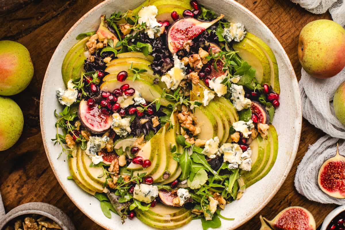 Pear Salad with Walnuts, Blue Cheese, Mixed Greens, Pomegranate, Figs, and Honey-Dijon Dressing - in a bowl.