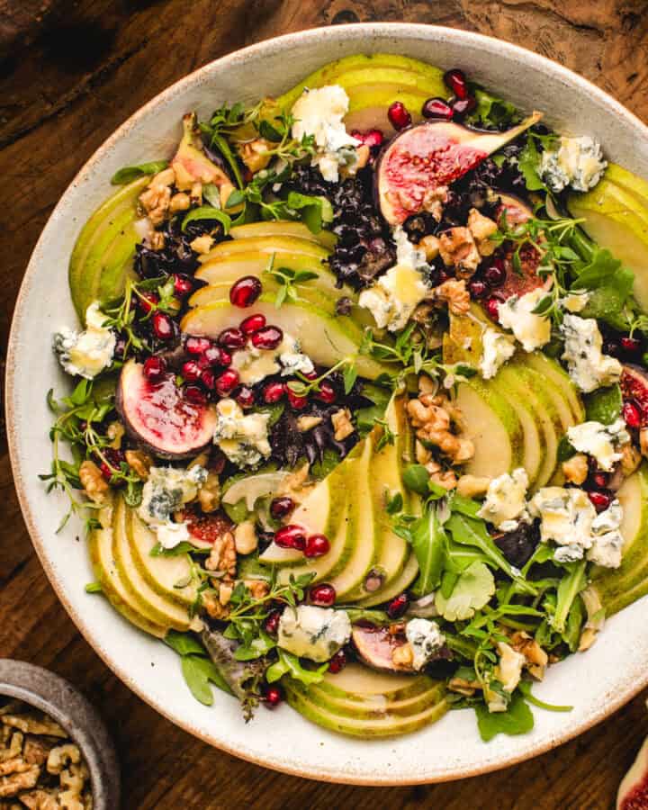 Pear Salad with Walnuts, Blue Cheese, Mixed Greens, Pomegranate, Figs, and Honey-Dijon Dressing - in a bowl.