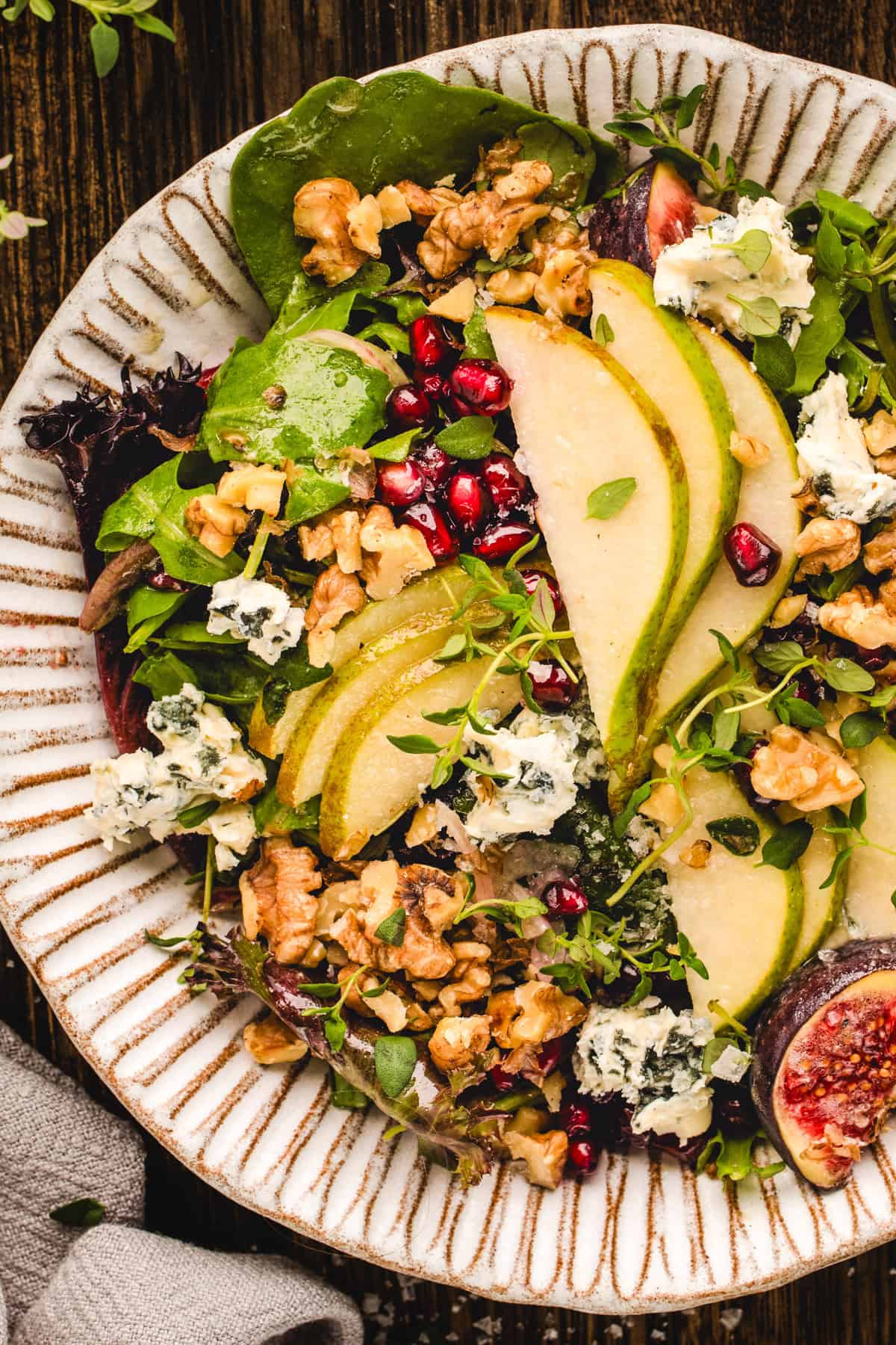 Pear Salad with Walnuts, Blue Cheese, Mixed Greens, Pomegranate, Figs, and Honey-Dijon Dressing - in a bowl.
