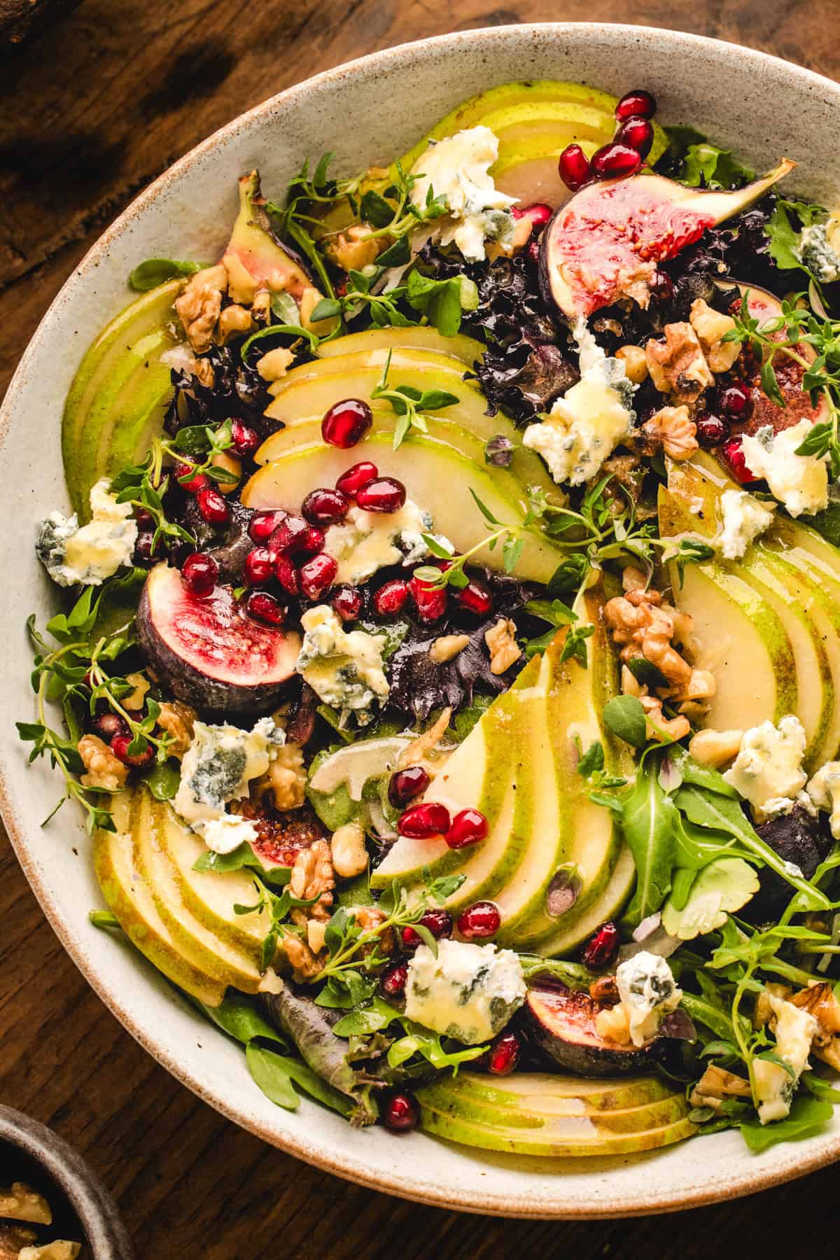 Pear Salad with Walnuts, Blue Cheese, Mixed Greens, Pomegranate, Figs, and Honey-Dijon Dressing - in a bowl.