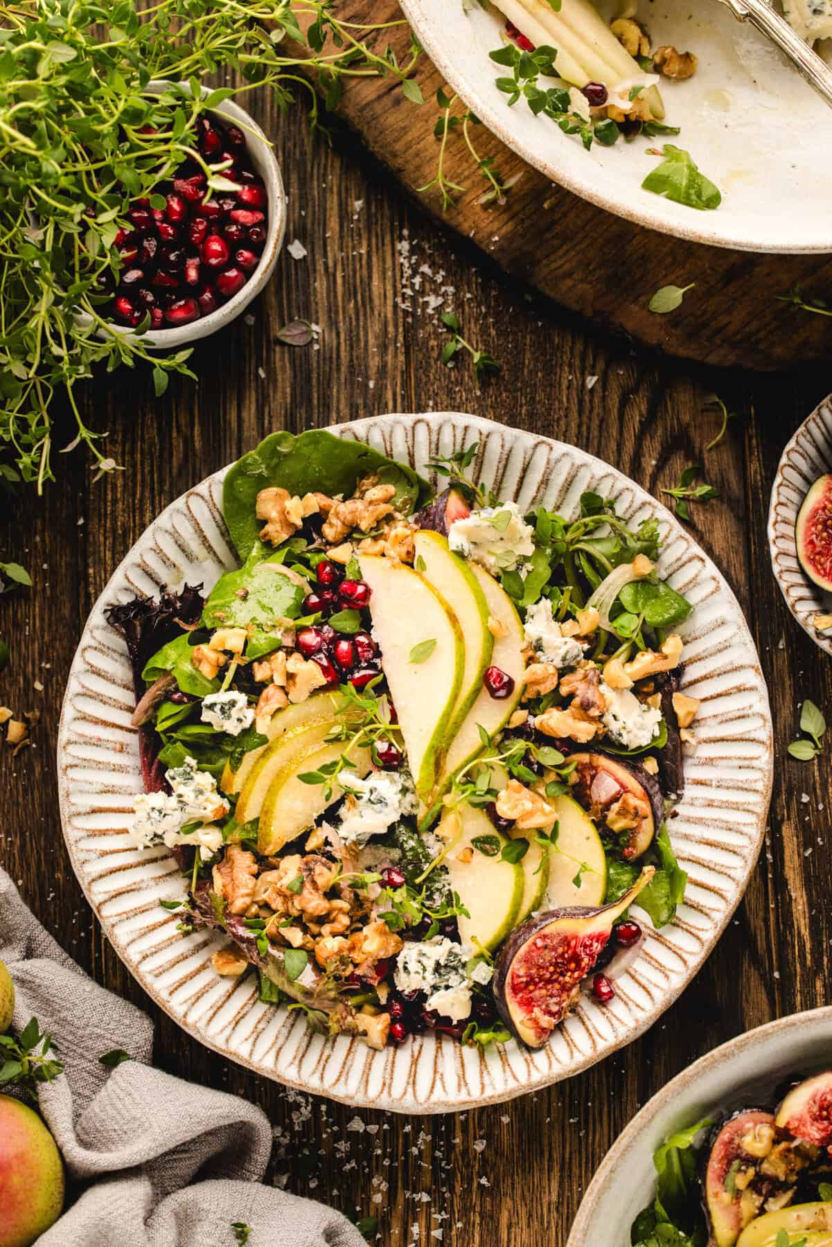 Pear Salad with Walnuts, Blue Cheese, Mixed Greens, Pomegranate, Figs, and Honey-Dijon Dressing - in a bowl.