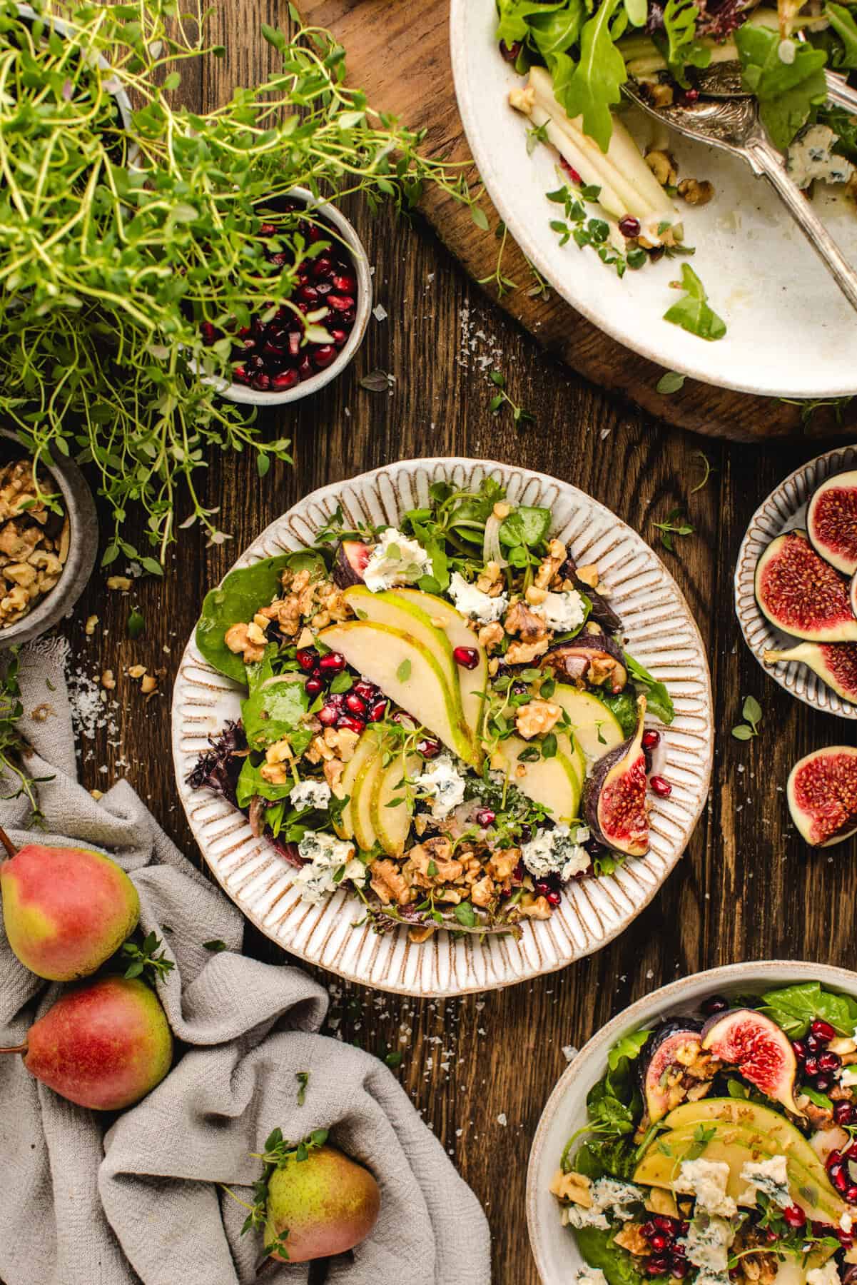 Pear Salad with Walnuts, Blue Cheese, Mixed Greens,  Pomegranate, Figs, and Honey-Dijon Dressing - in a bowl.
