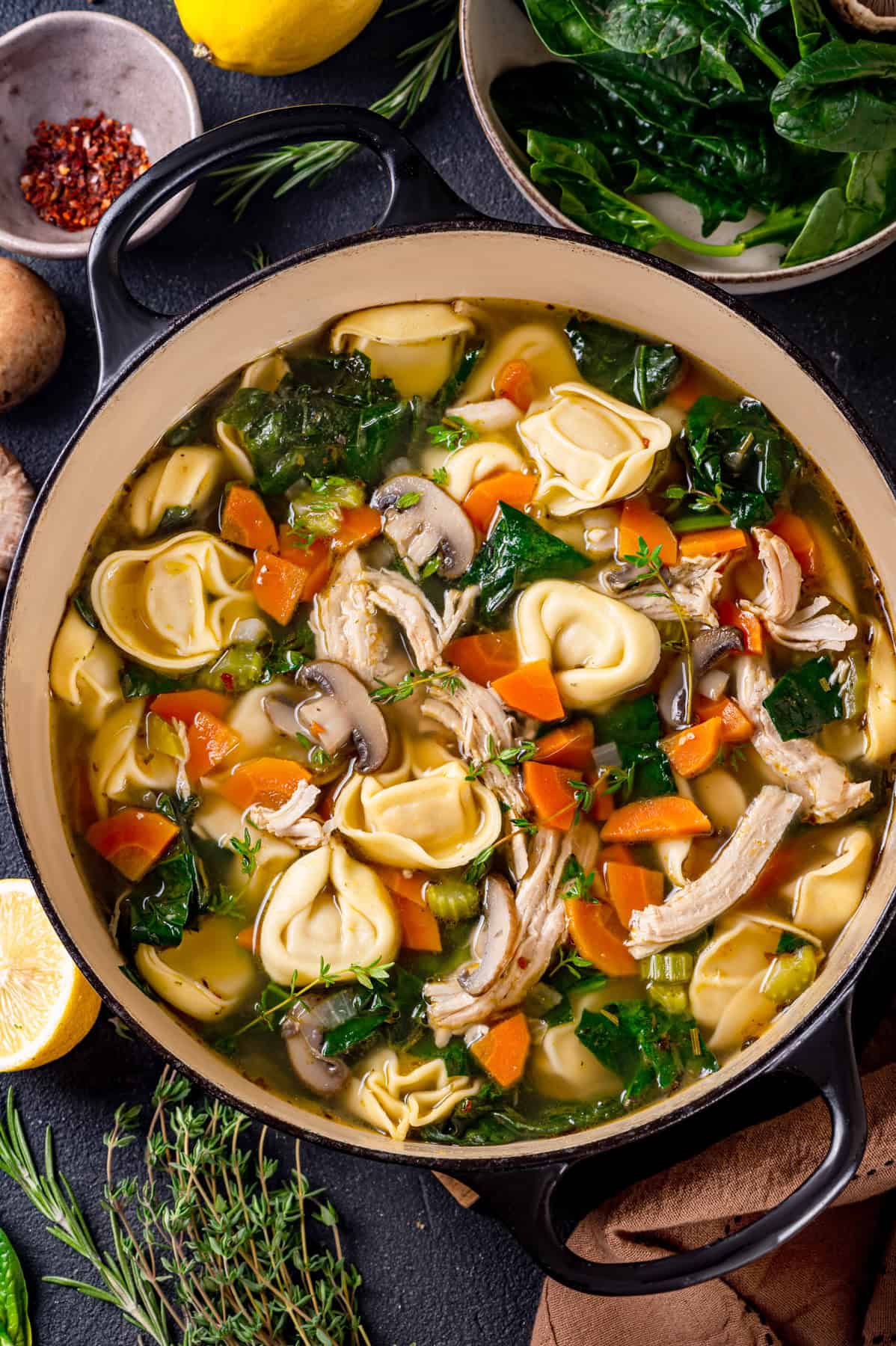 Chicken tortellini soup with spinach, carrots, mushrooms, and lemon - in a soup pot.