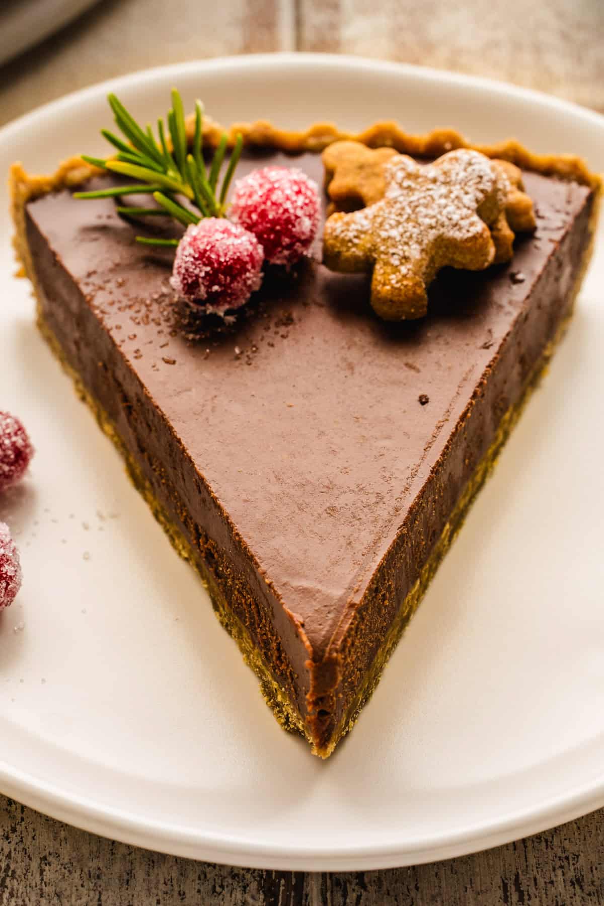 A slice of Gingerbread Cookie Chocolate Tart on a plate.