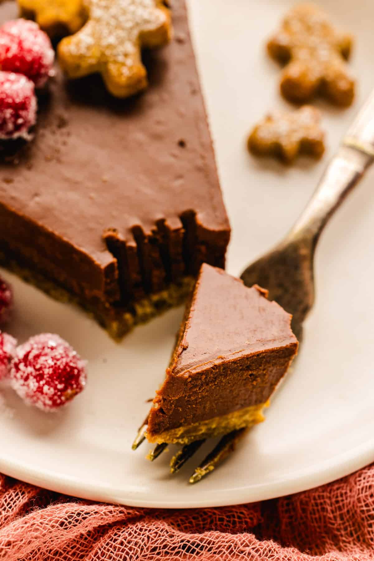 A slice of Gingerbread Cookie Chocolate Tart with a fork on a plate.