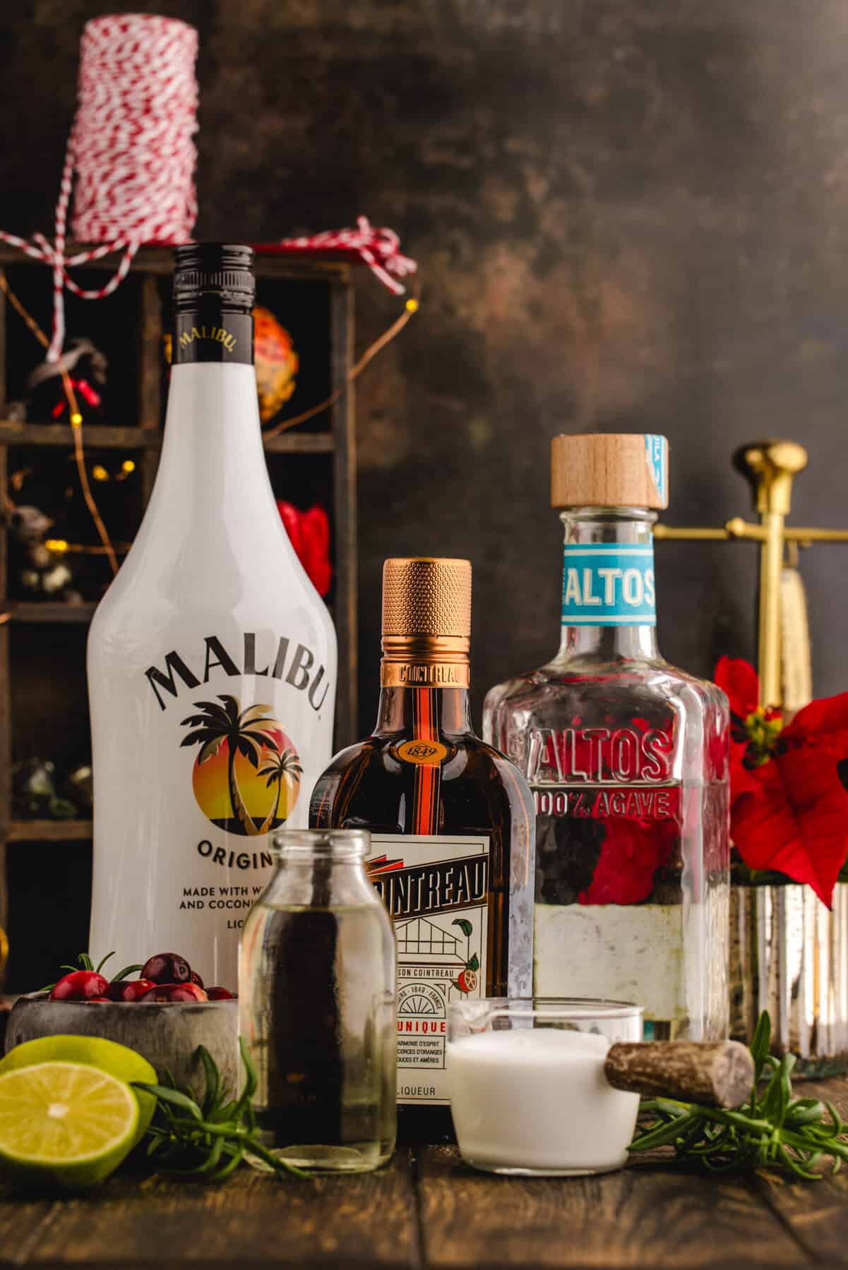 The Ingredients (alcohol bottles, fresh cranberries) for the White Christmas Margarita.