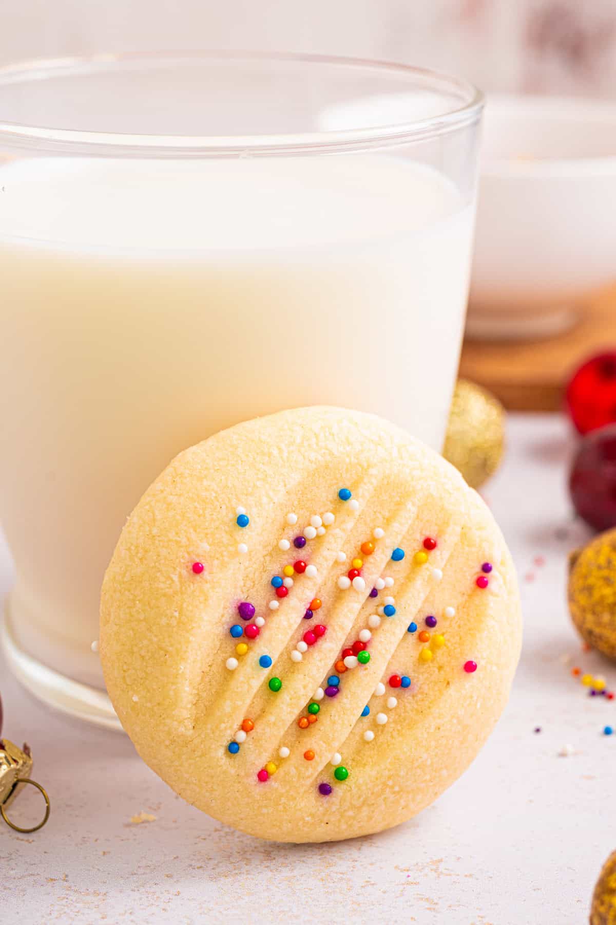 Whipped Shortbread Cookie leaning against a full glass of milk.