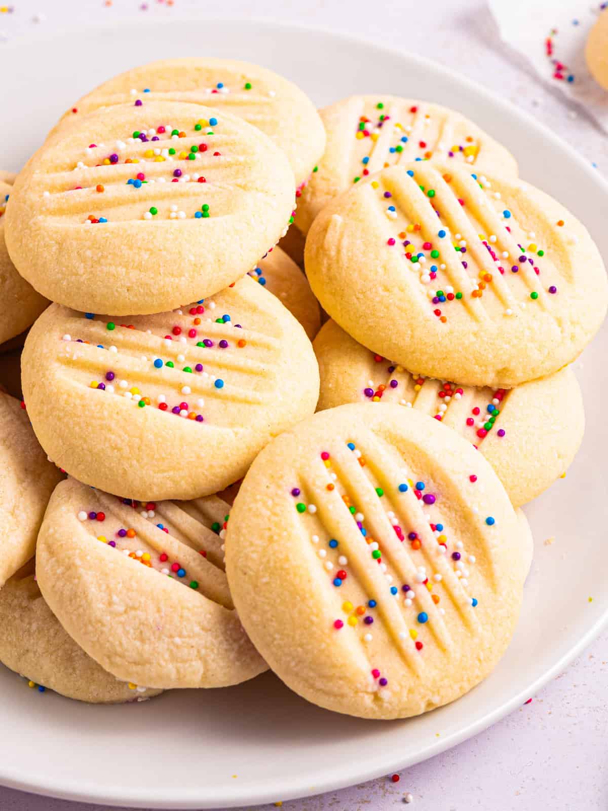 Whipped Shortbread Cookies with sprinkles - on a white plate.