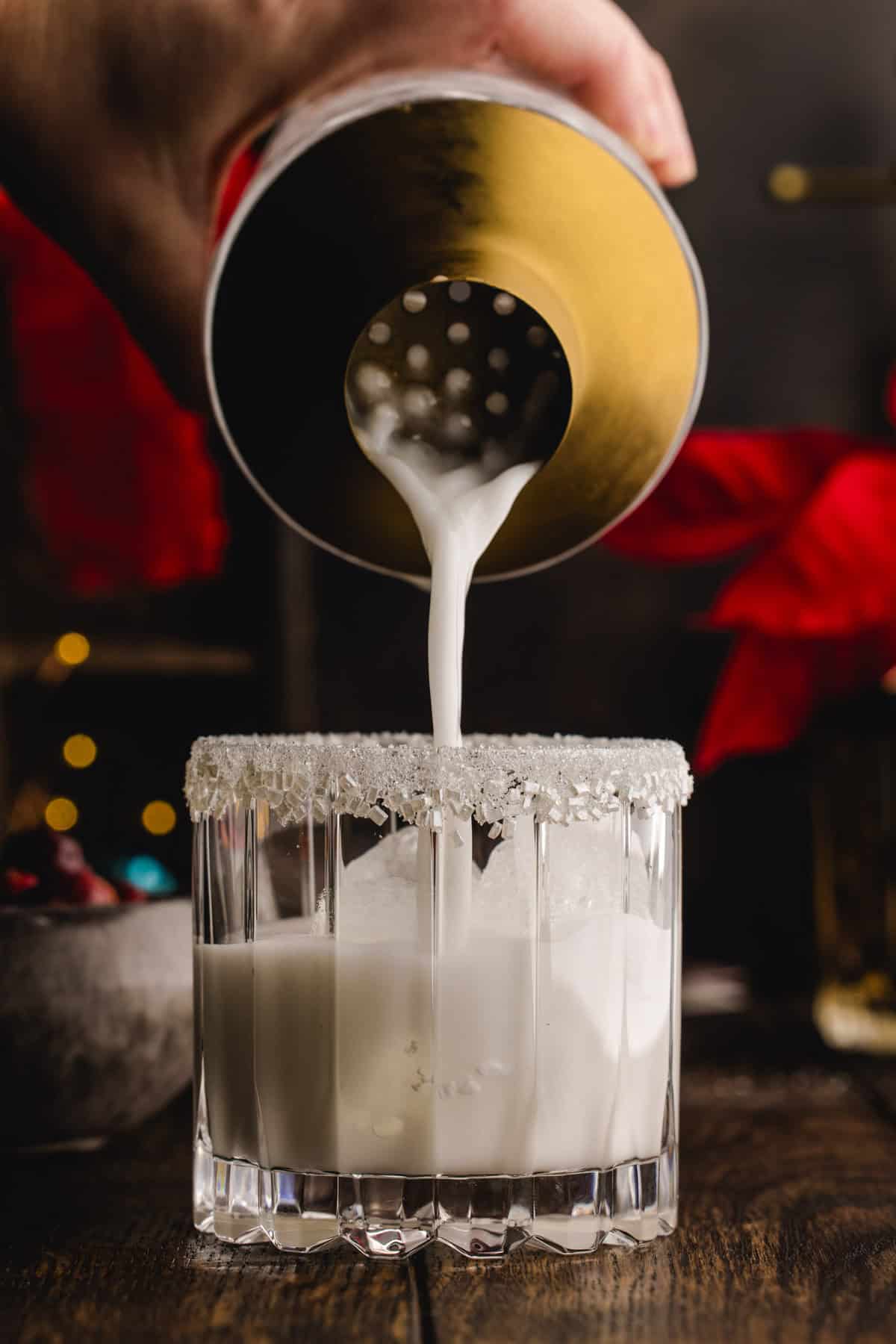 Pouring the margarita from the cocktail shaker into a glass.