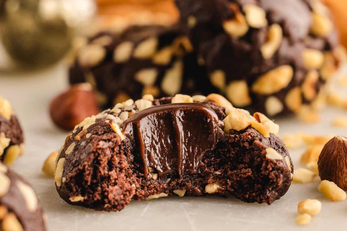 Chocolate Hazelnut Thumbprint Cookies Chocolate Hazelnut Thumbprint Cookie (bitten) - on a white surface.