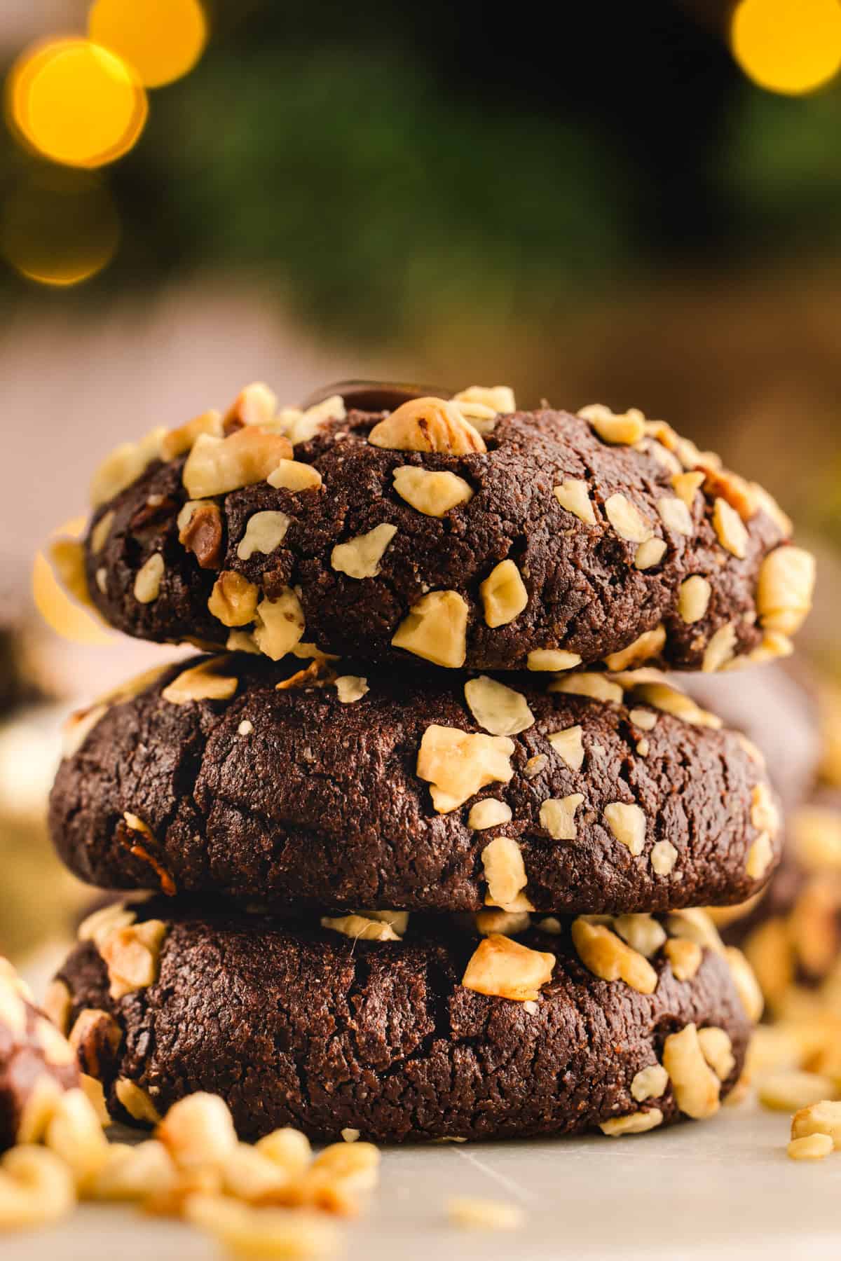 Chocolate Hazelnut Thumbprint Cookies A stack of 3 Chocolate Hazelnut Thumbprint Cookies on a white surface.