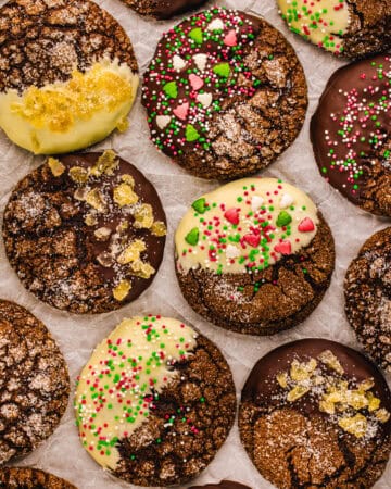 Ginger molasses cookies (some covered with white chocolate, some with dark chocolate, topped with sprinkles or crystallized ginger) - on a white background.