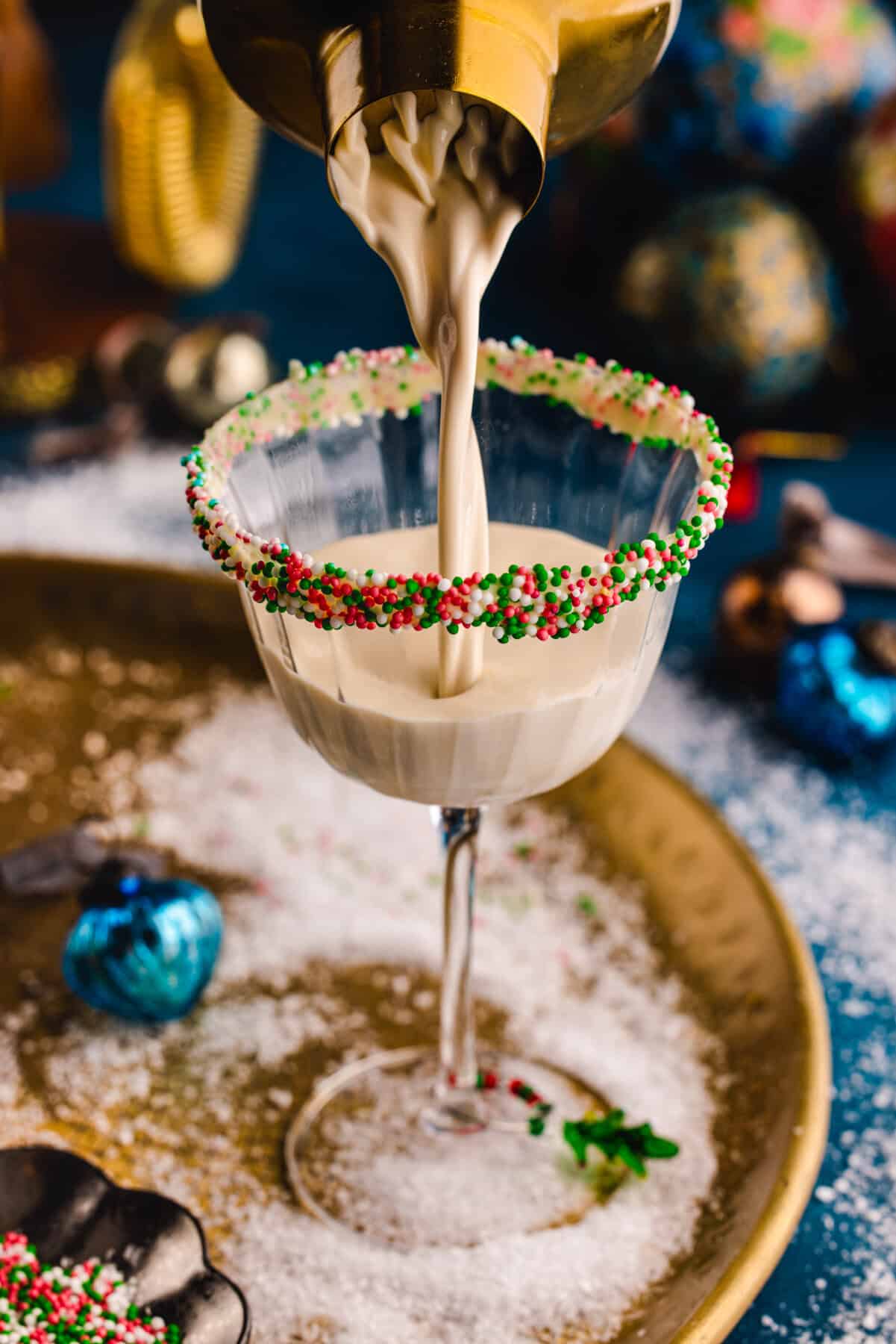 Pouring a cocktail into a glass (with festive sprinkles on a rim).
