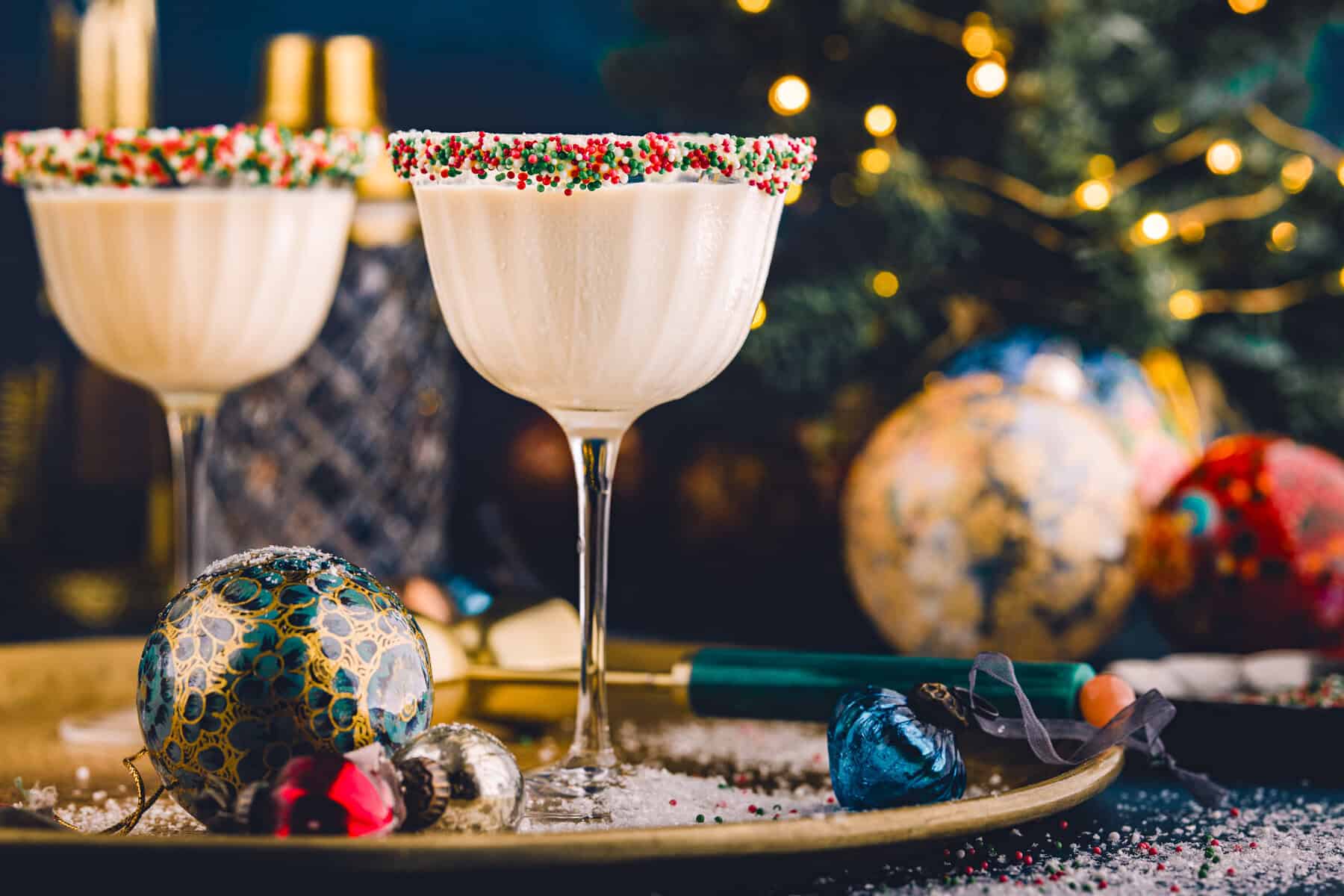 2 glasses of Sugar Cookie Martini (with holiday sprinkles on the rim) - on a festive tray.