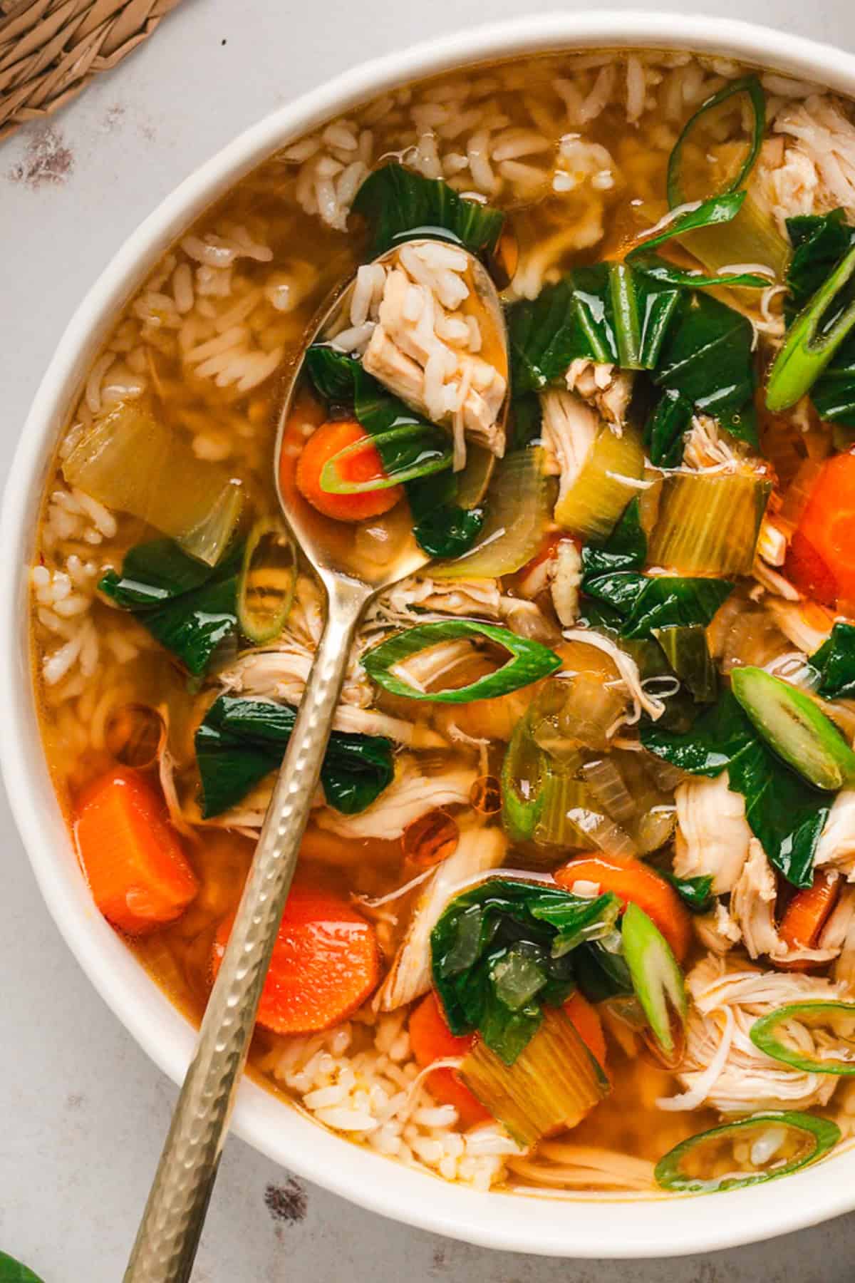 Asian Chicken and Rice Soup Asian Chicken and Rice Soup with Carrots, Bok Choy, and Rice - in a bowl with a spoon.