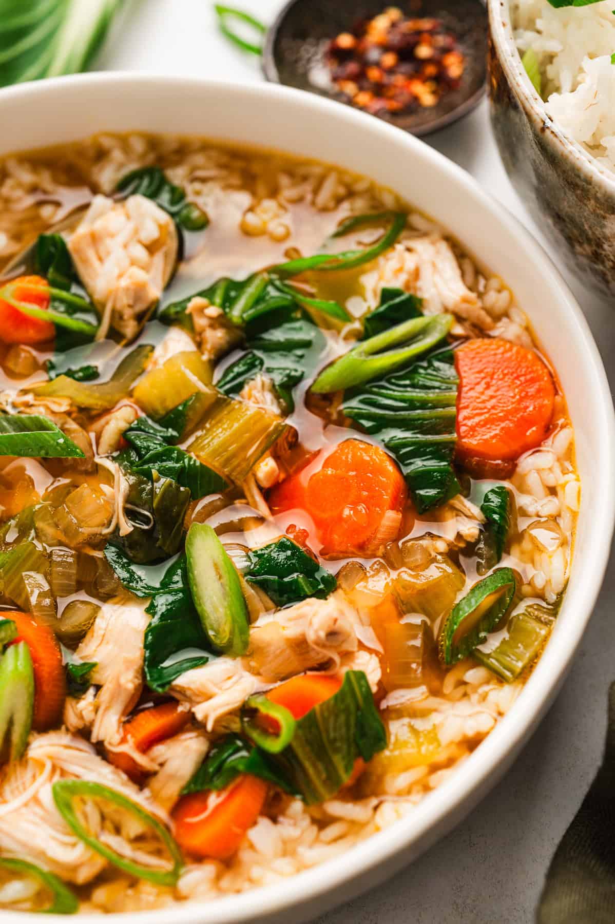 Asian Chicken and Rice Soup Asian Chicken and Rice Soup with Carrots, Bok Choy, and Rice - in a bowl.
