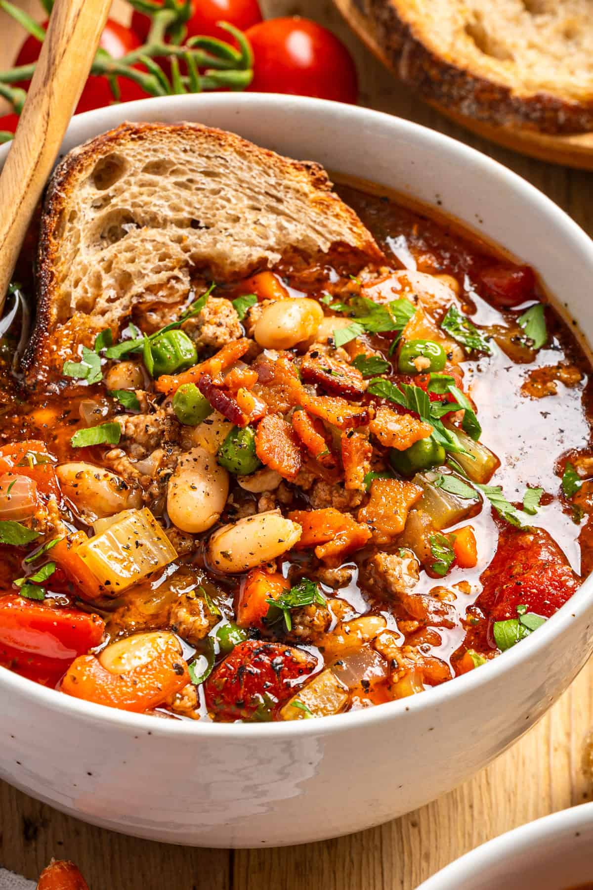 Ground Turkey Soup with Carrots, Peas, Beans, Bacon, Tomatoes, Herbs - in a white bowl.