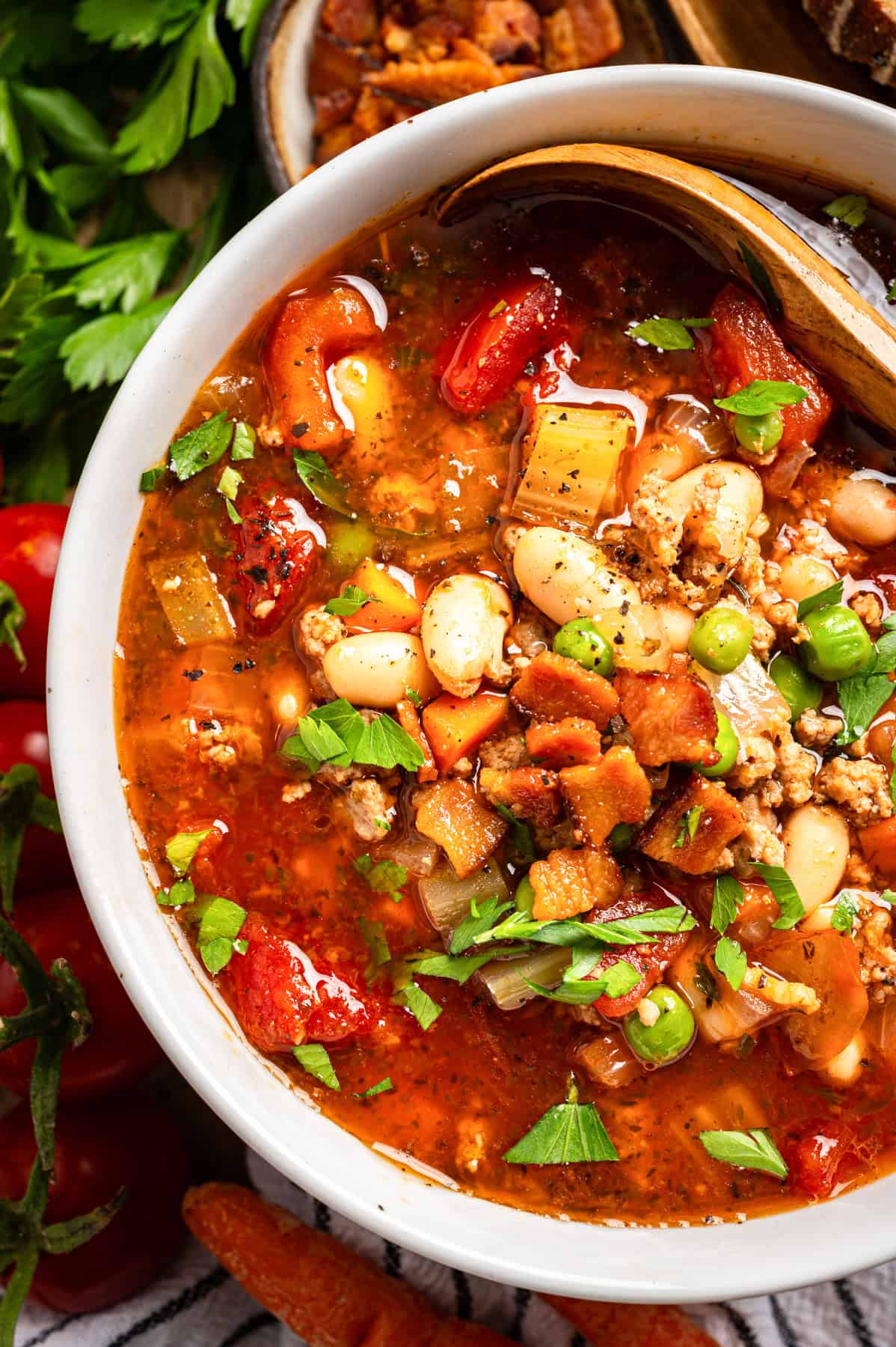 Ground Turkey Soup with Carrots, Peas, Beans, Bacon, Tomatoes, Herbs - in a white bowl.