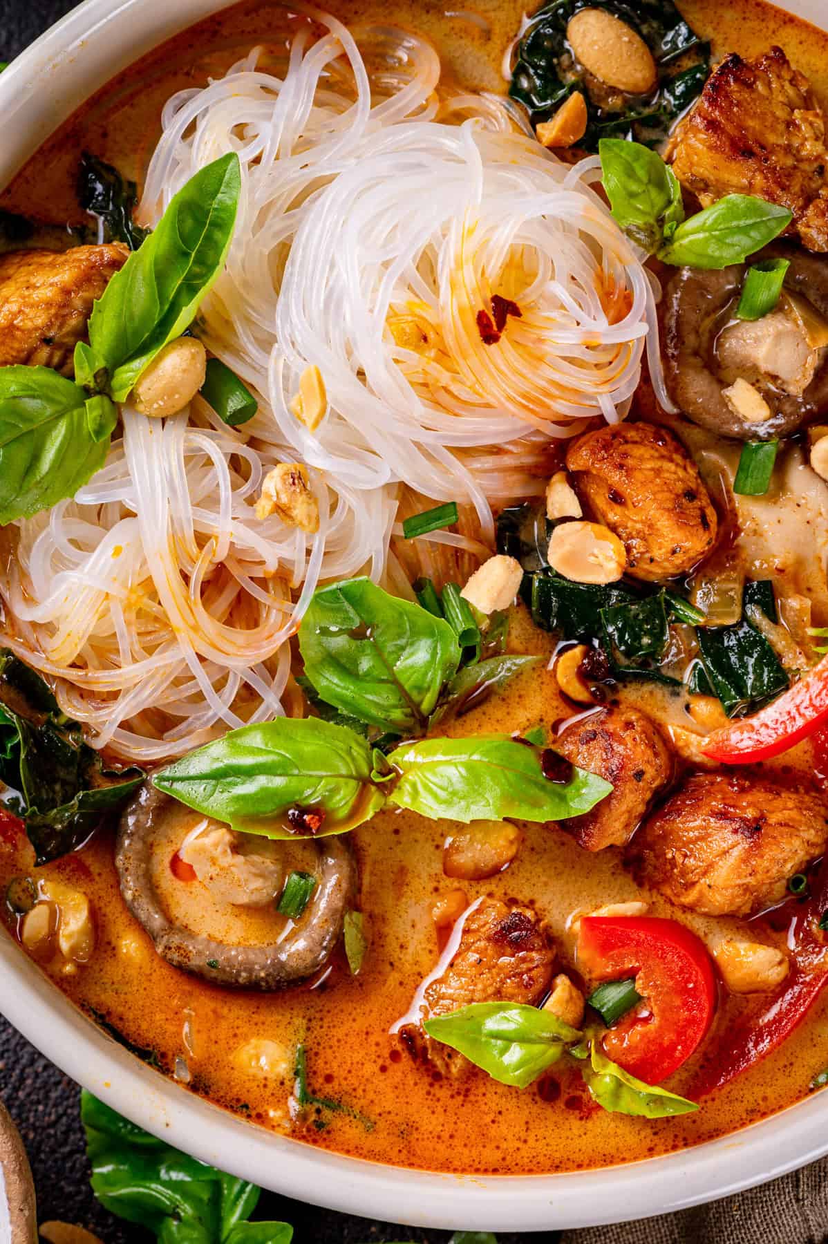 Thai chicken curry soup (with noodles, red bell peppers, and mushrooms) - in a bowl.