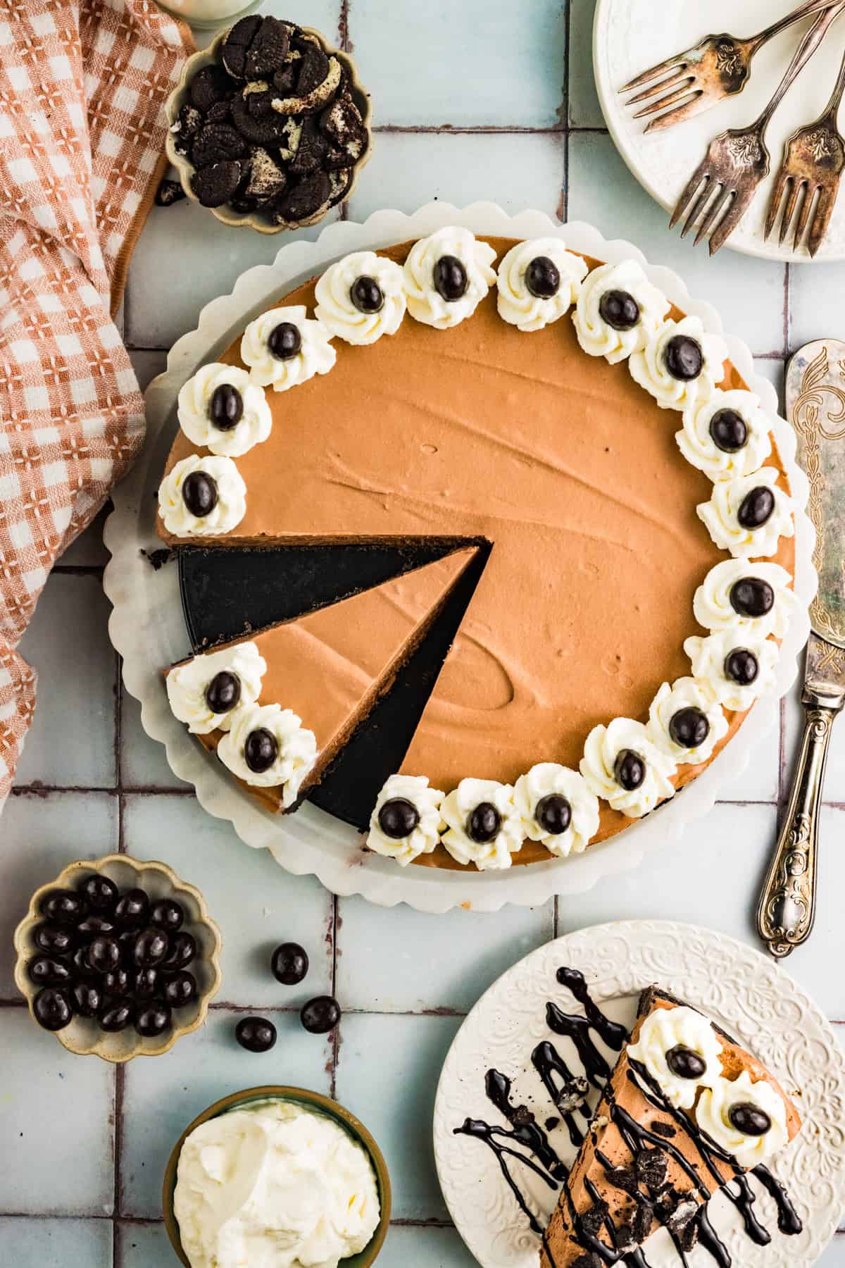 Mudslide Pie Mudslide Pie, topped with whipped cream and chocolate-covered espresso beans, with one slice removed and served on a plate. Surrounding the pie are forks, a knife, cookies, whipped cream, and a checked cloth napkin.