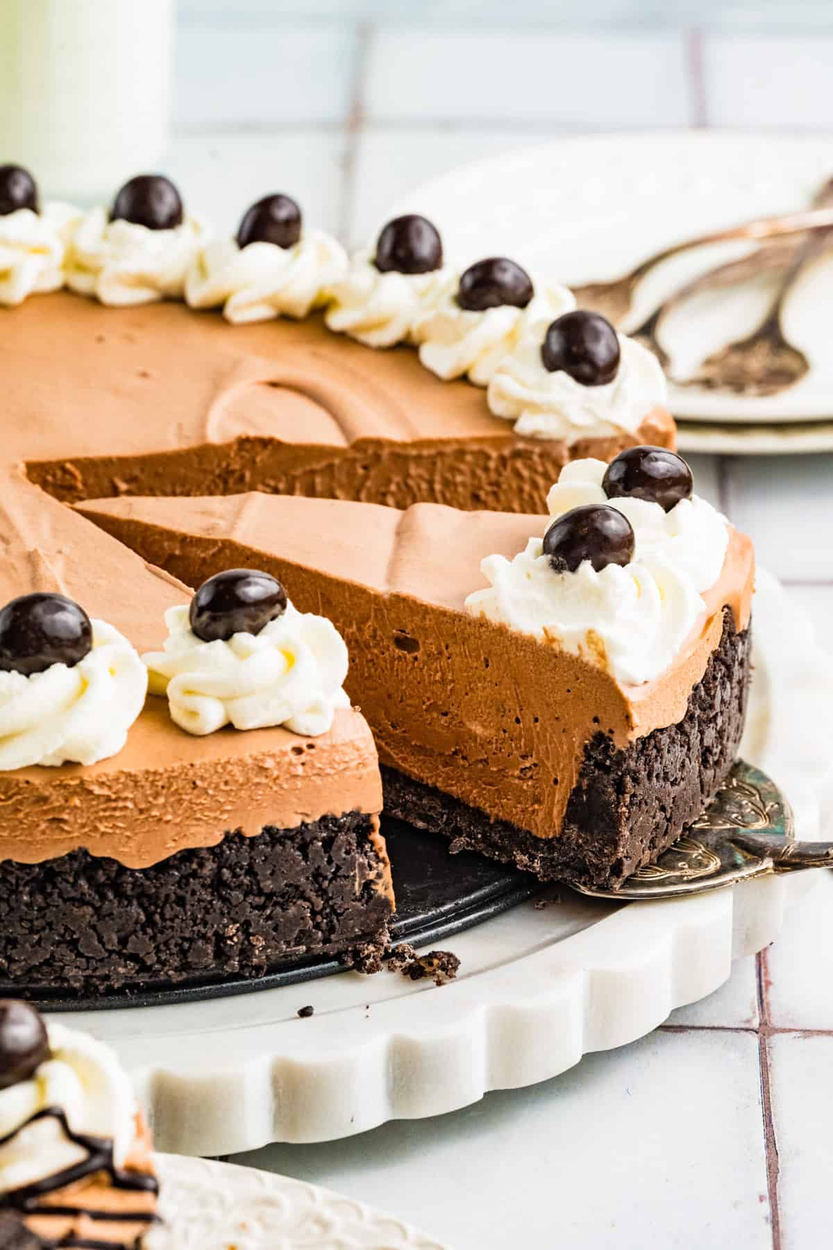 Mudslide Pie Mudslide Pie with a cookie crust, topped with whipped cream rosettes and chocolate-covered espresso beans. A slice is being lifted from the cake.