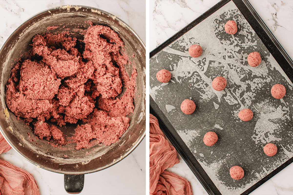 A bowl of pink cookie dough sits next to a baking tray lined with parchment paper, holding evenly spaced balls of the same pink dough, ready to be baked.
