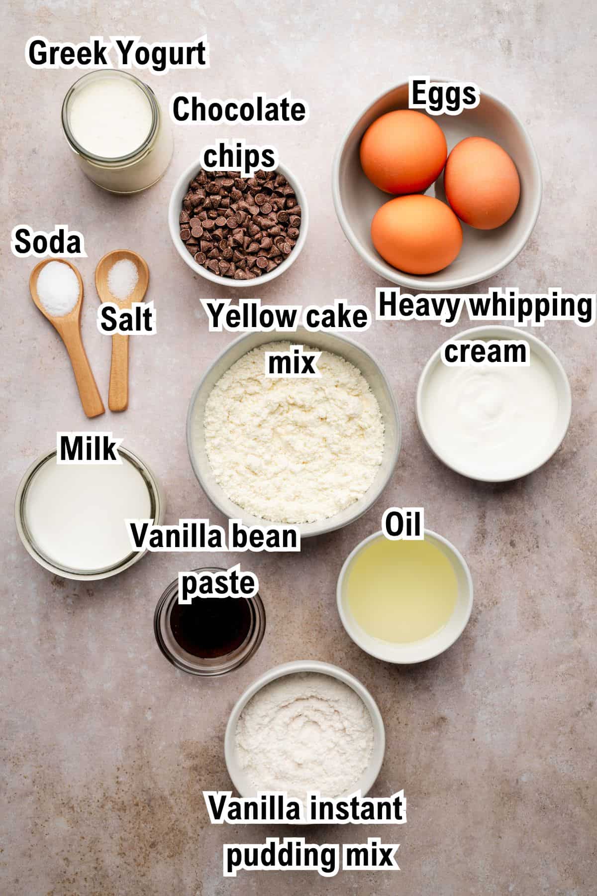 This photo shows the ingredients for Chocolate Chip Bundt Cake, including Greek yogurt, chocolate chips, eggs, soda, salt, yellow cake mix, heavy whipping cream, milk, vanilla bean paste, oil, and vanilla instant pudding mix.
