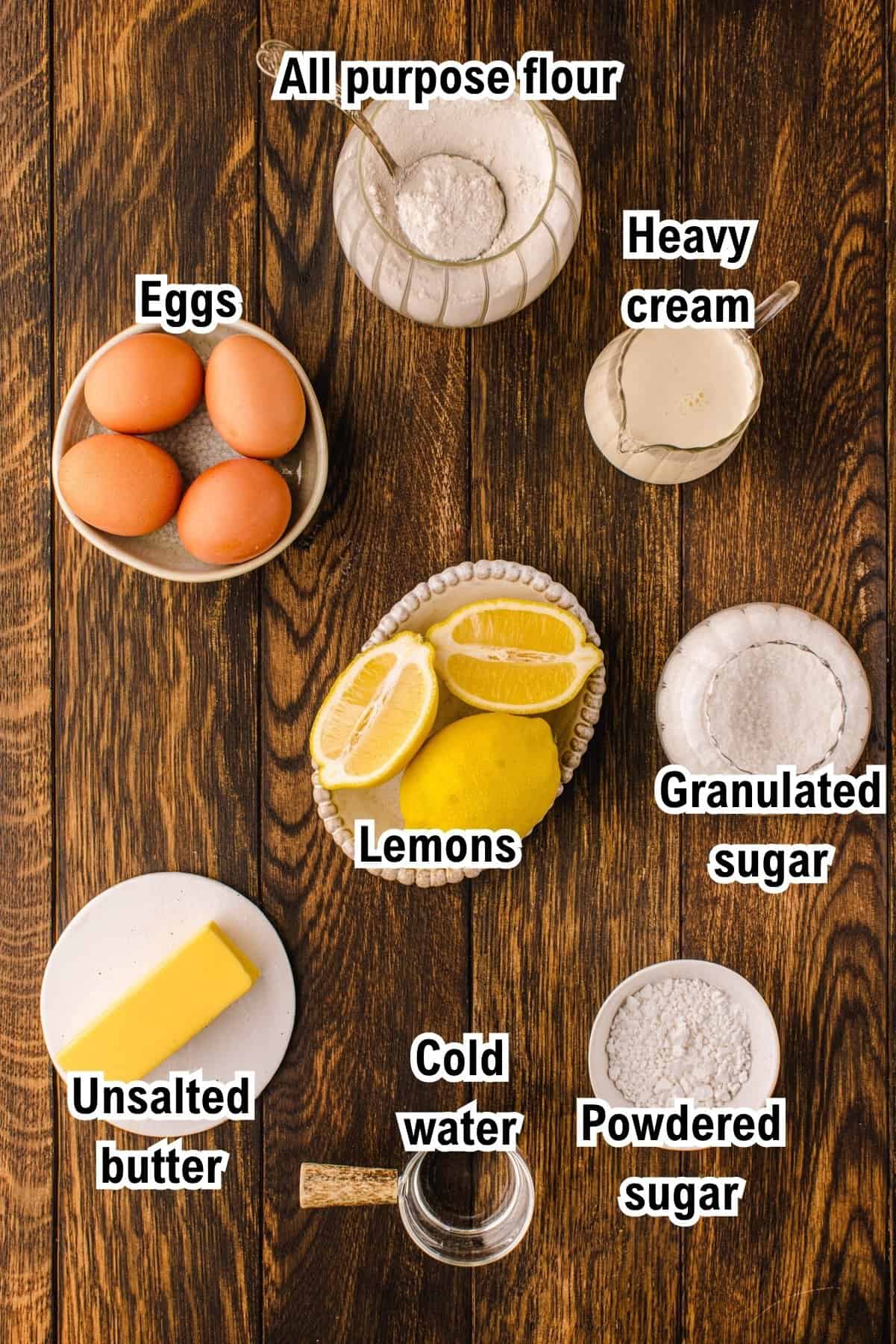 The Ingredients for Lemon Tart This photo shows the ingredients for Lemon Tart, including all-purpose flour, eggs, lemons, unsalted butter, heavy cream, granulated sugar, cold water, and powdered sugar, each labeled.
