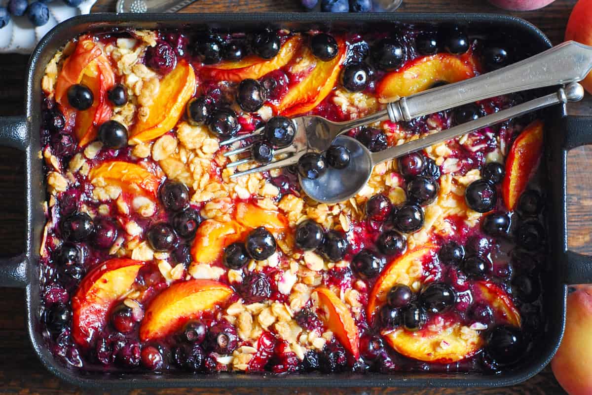 10 Peach Recipes So Good You'll Buy Extra Peaches Just to Make Them A baked blueberry peach crisp in a rectangular dish, topped with sliced peaches, whole blueberries, and a crumbly oat topping.