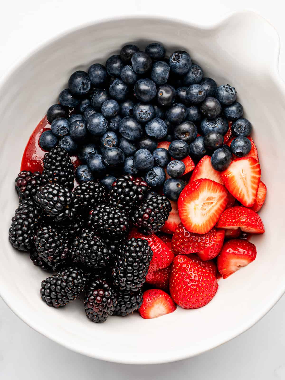 Berry Pie A white bowl filled with fresh blueberries, blackberries, and sliced strawberries, arranged in sections.