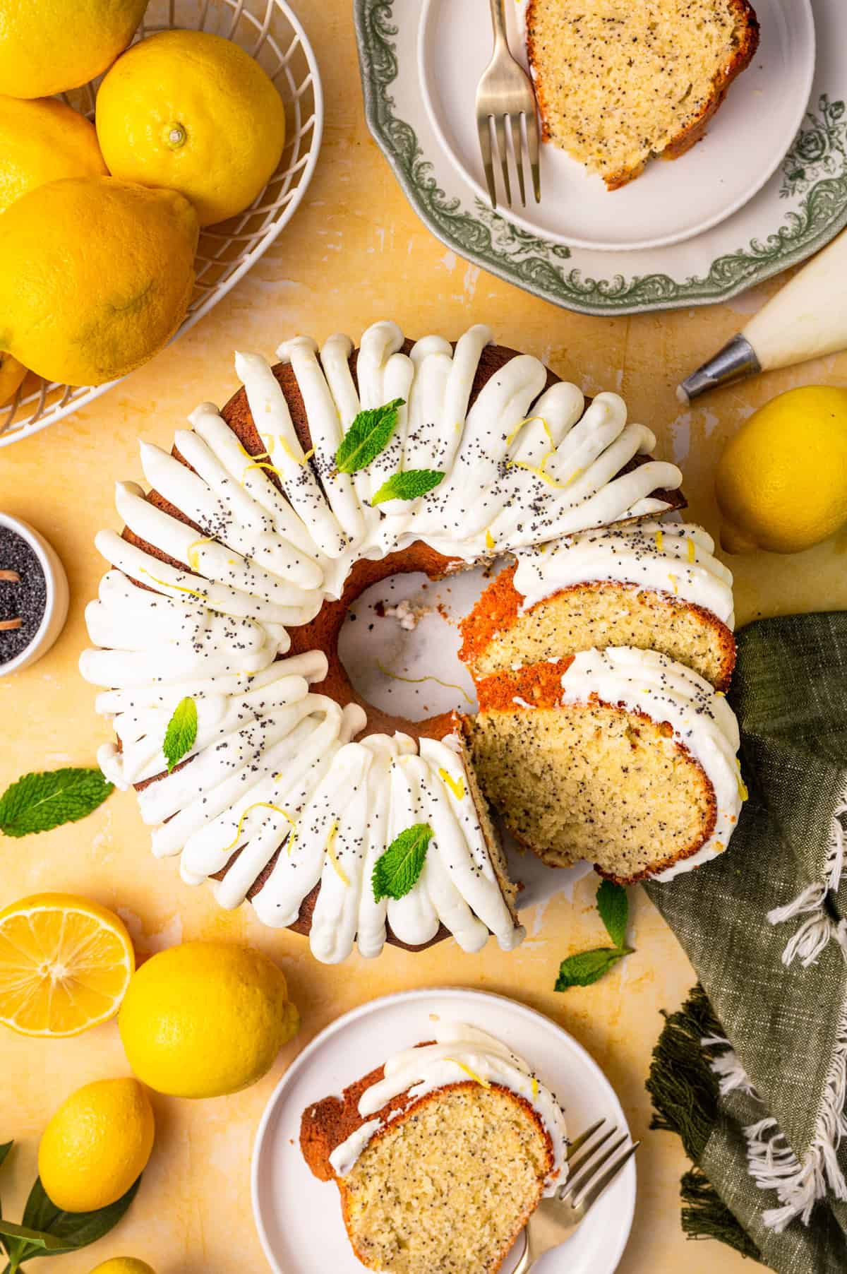Poppy Seed Lemon Bundt Cake A lemon poppy seed bundt cake with white icing, garnished with mint, is sliced on a table.