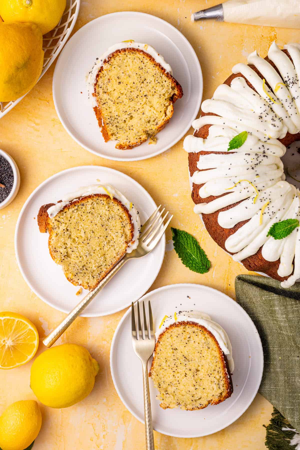 Poppy Seed Lemon Bundt Cake Three slices of lemon poppy seed bundt cake with white icing on plates with forks.