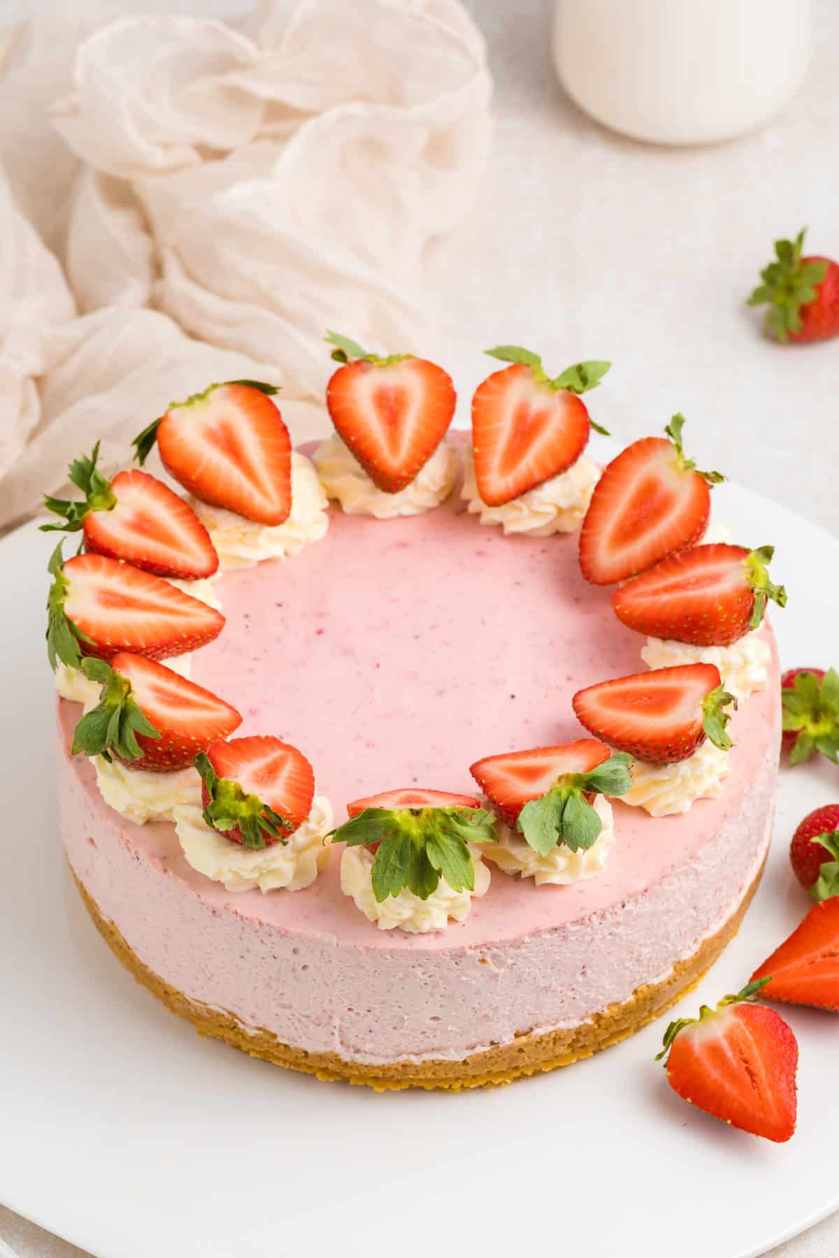 A strawberry cheesecake topped with halved fresh strawberries and whipped cream.