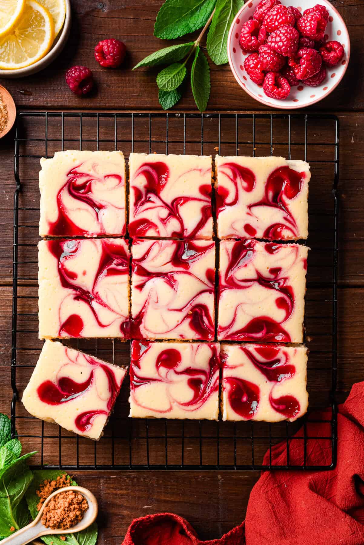 Raspberry swirl cheesecake bars on a cooling rack, with one bar slightly pulled out. 