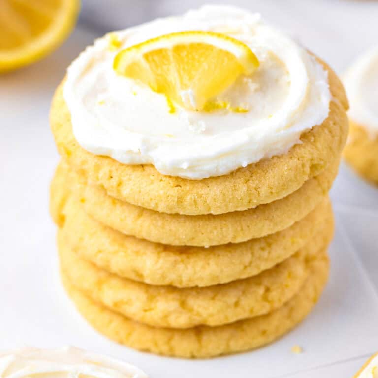 A stack of five lemon cookies topped with white frosting and a small lemon wedge.