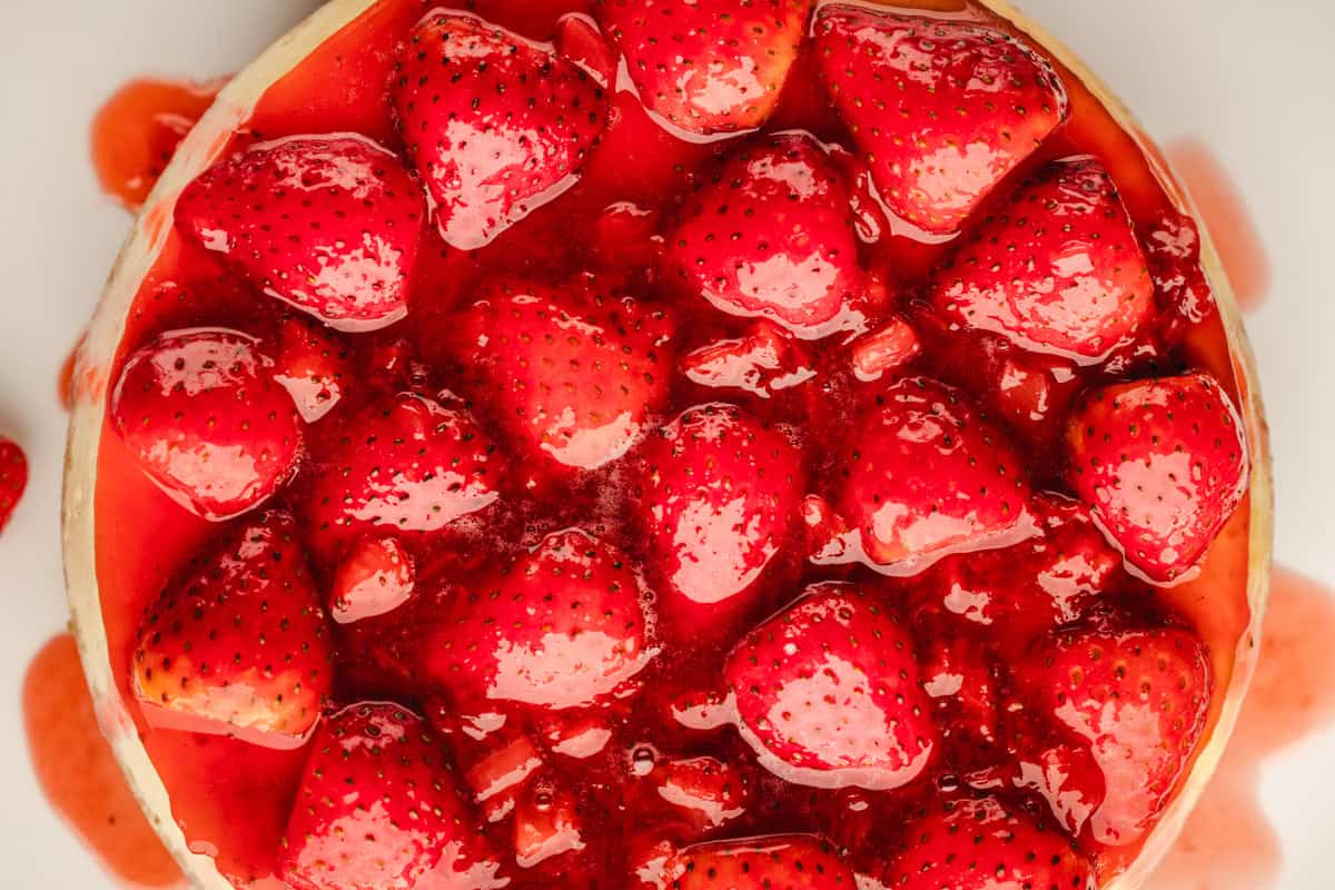 Classic New York-Style Cheesecake Close-up of a strawberry-topped dessert, with glossy red glaze and whole strawberries.
