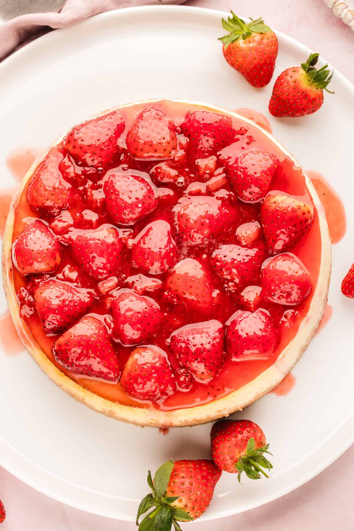 Classic New York-Style Cheesecake A round cheesecake topped with whole glazed strawberries and strawberry sauce.
