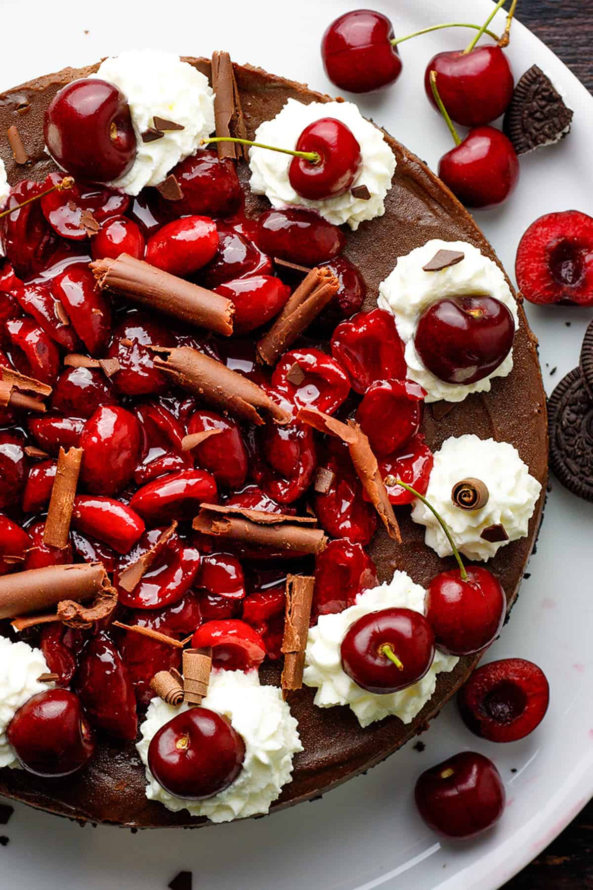 Black Forest Cheesecake A chocolate cherry cake topped with fresh cherries, whipped cream, chocolate curls, and a glossy cherry glaze.