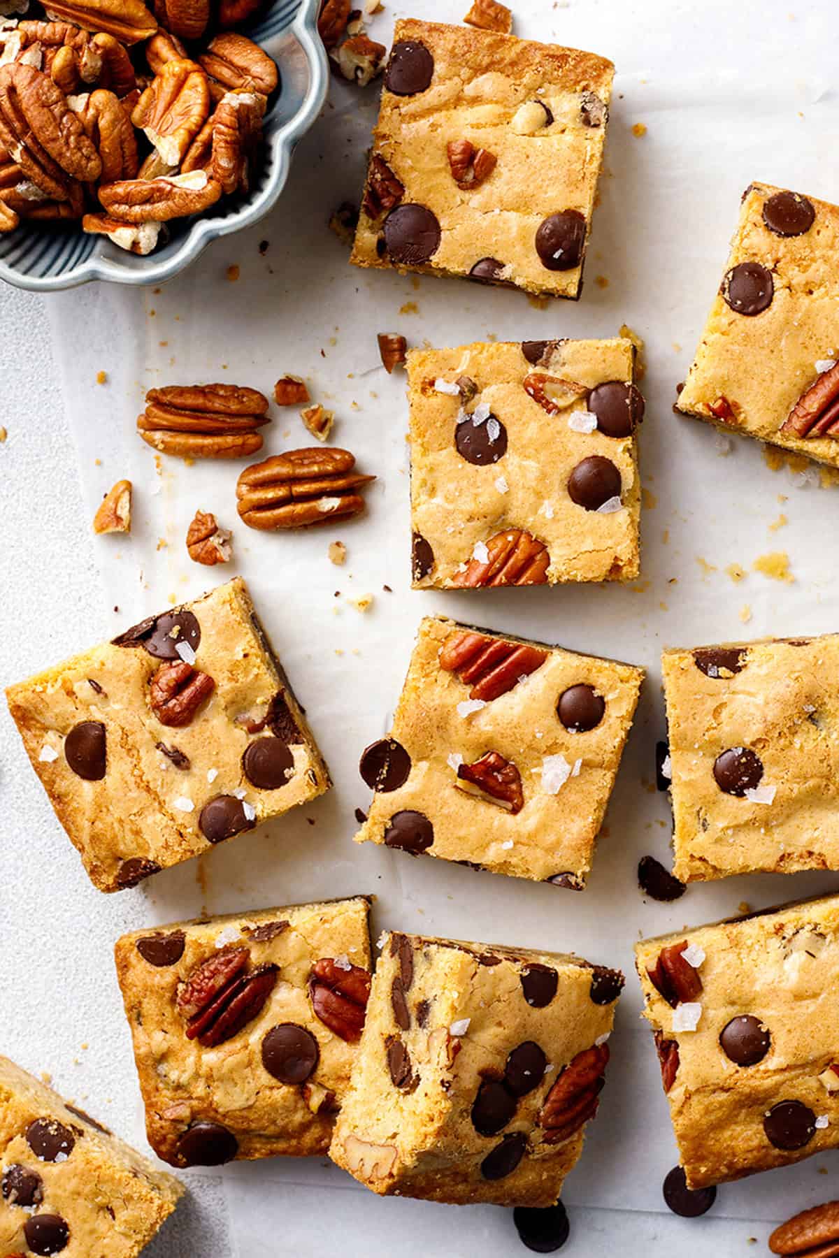 Blondies Blondie bars with chocolate chips and pecans are arranged on parchment paper.