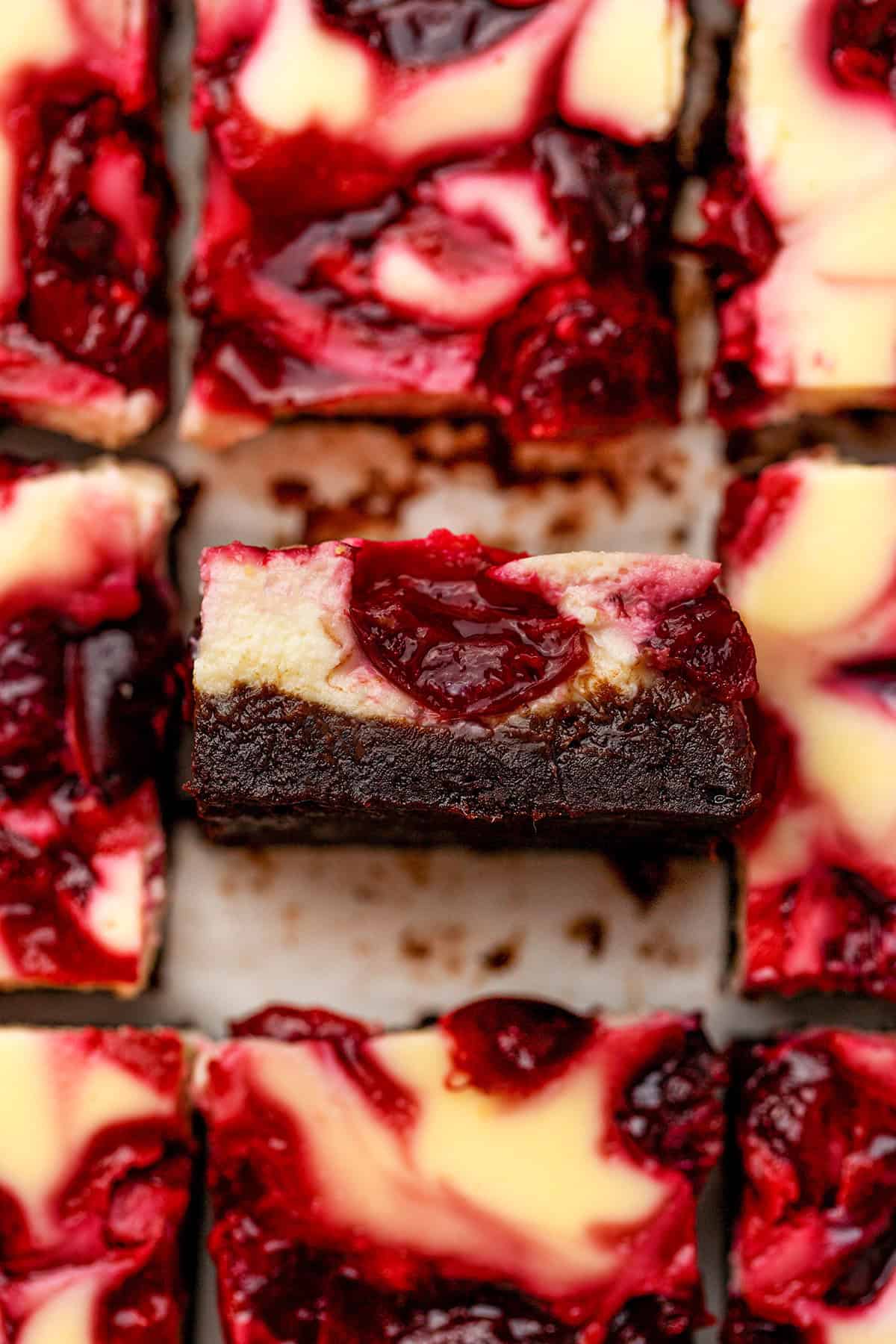 Cherry Cheesecake Brownies A close-up of cherry cheesecake brownies, with a brownie bottom, creamy cheesecake layer, and a vibrant cherry swirl on top.