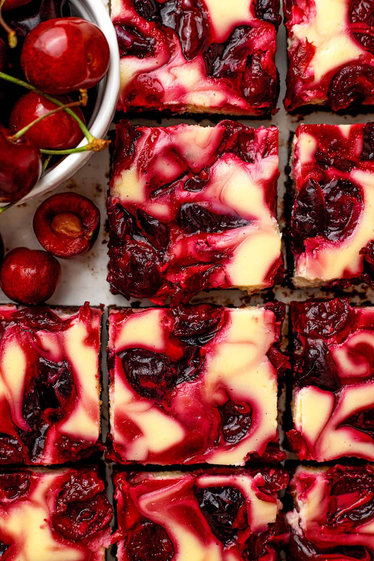 Cherry Cheesecake Brownies Close-up of cherry cheesecake brownies, swirled with vibrant red cherry sauce and creamy cheesecake, cut into squares.