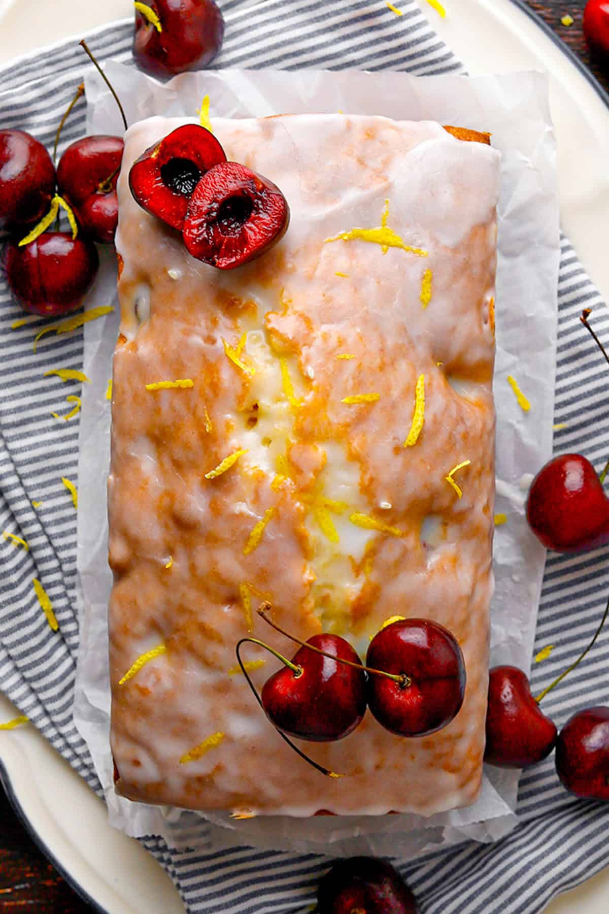Cherry Loaf Cake Glazed loaf cake topped with lemon zest and fresh cherries.