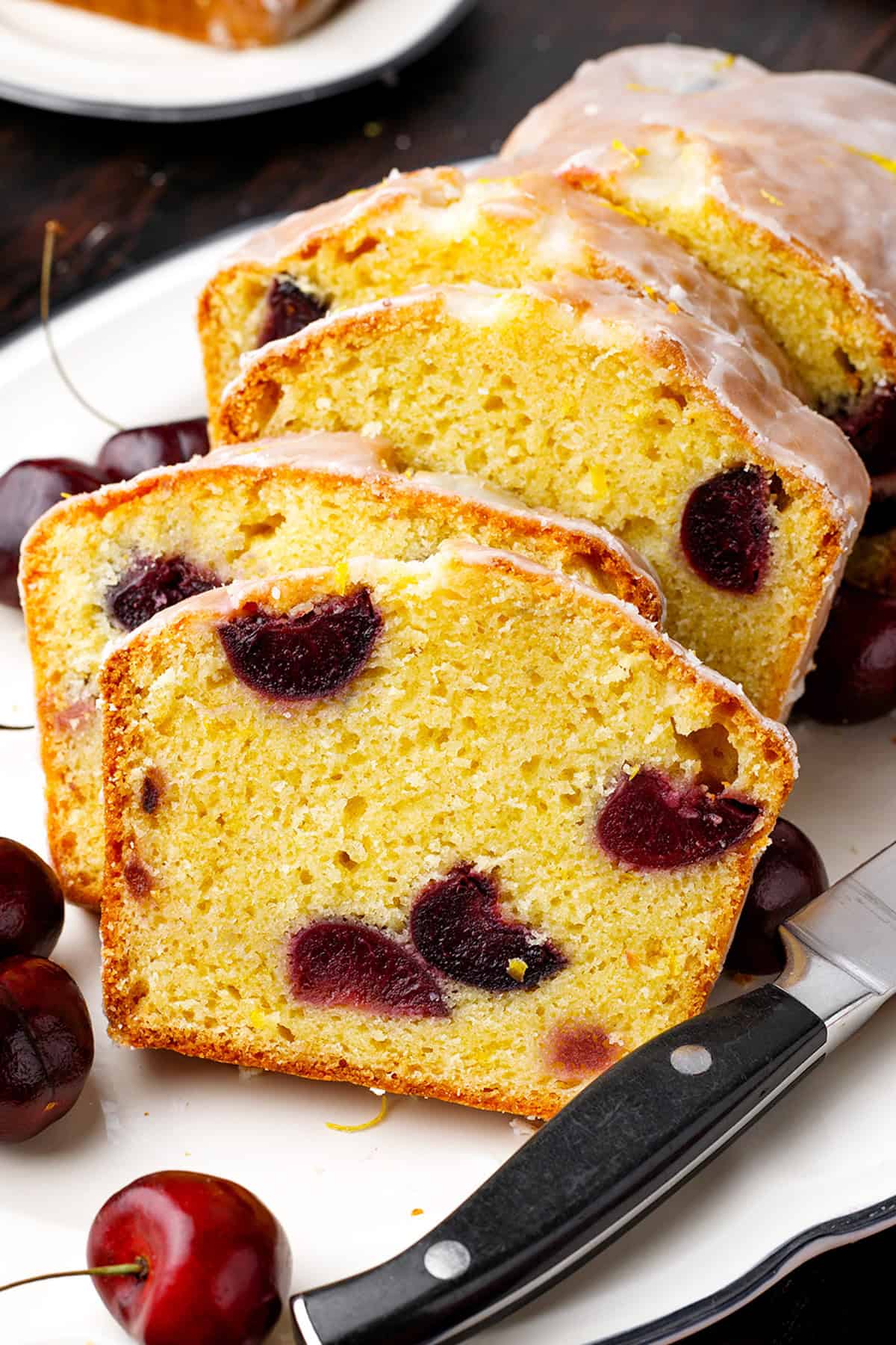 Cherry Loaf Cake Sliced cherry loaf cake with glaze on a white plate.